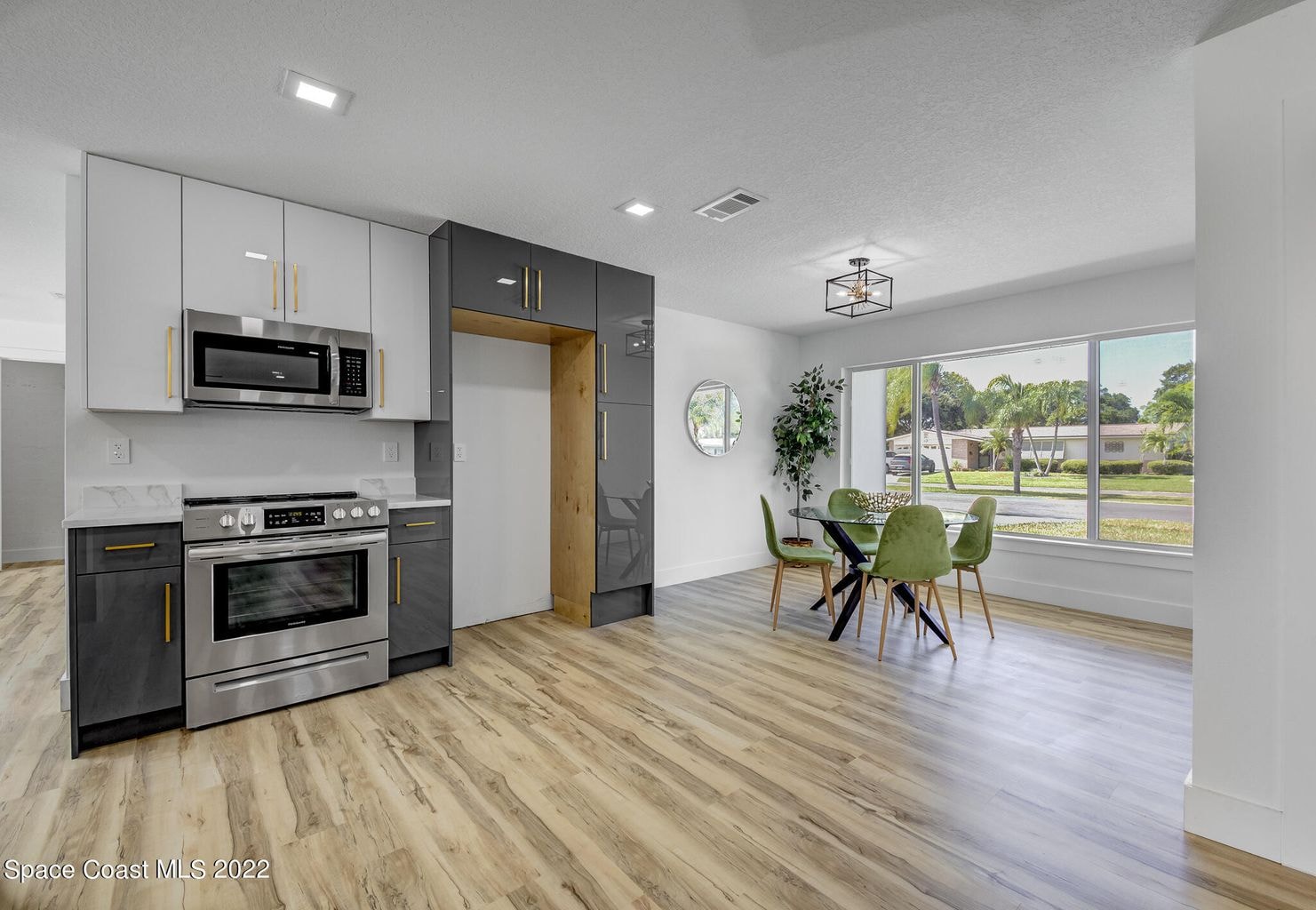 Two-tone gray and white flat panel kitchen with marble waterfall island and gold hardware by 1 Stop Cabinets