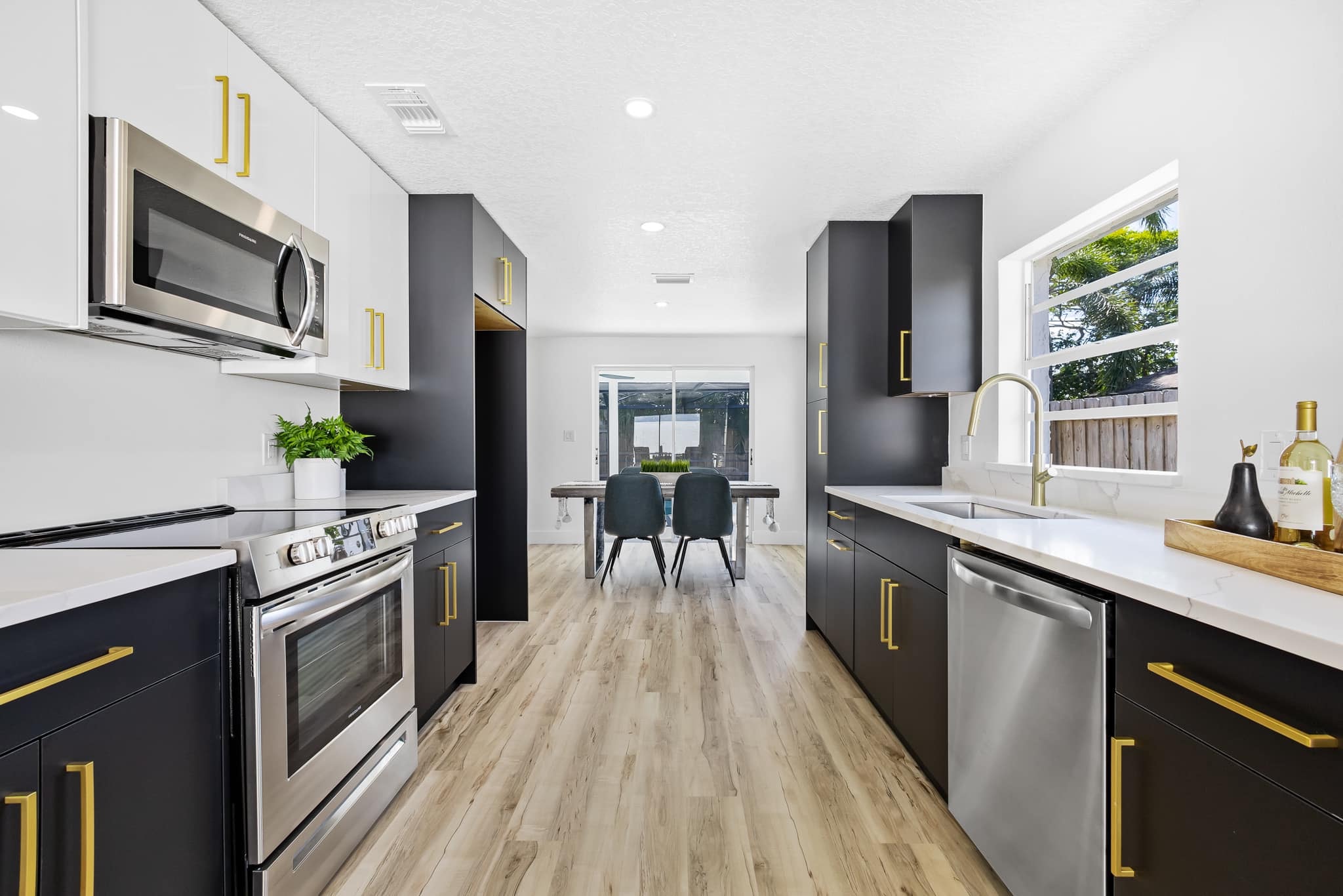 Black flat panel galley kitchen with white quartz countertops and gold hardware by 1 Stop Cabinets