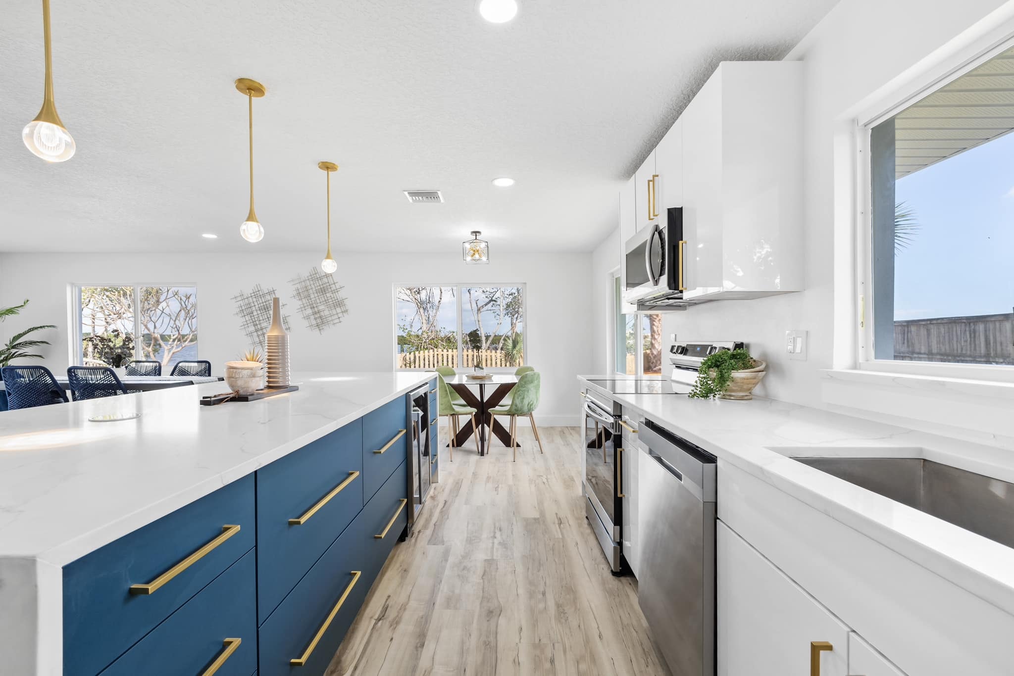 White and navy blue flat panel kitchen with quartz island and gold pendant lights by 1 Stop Cabinets