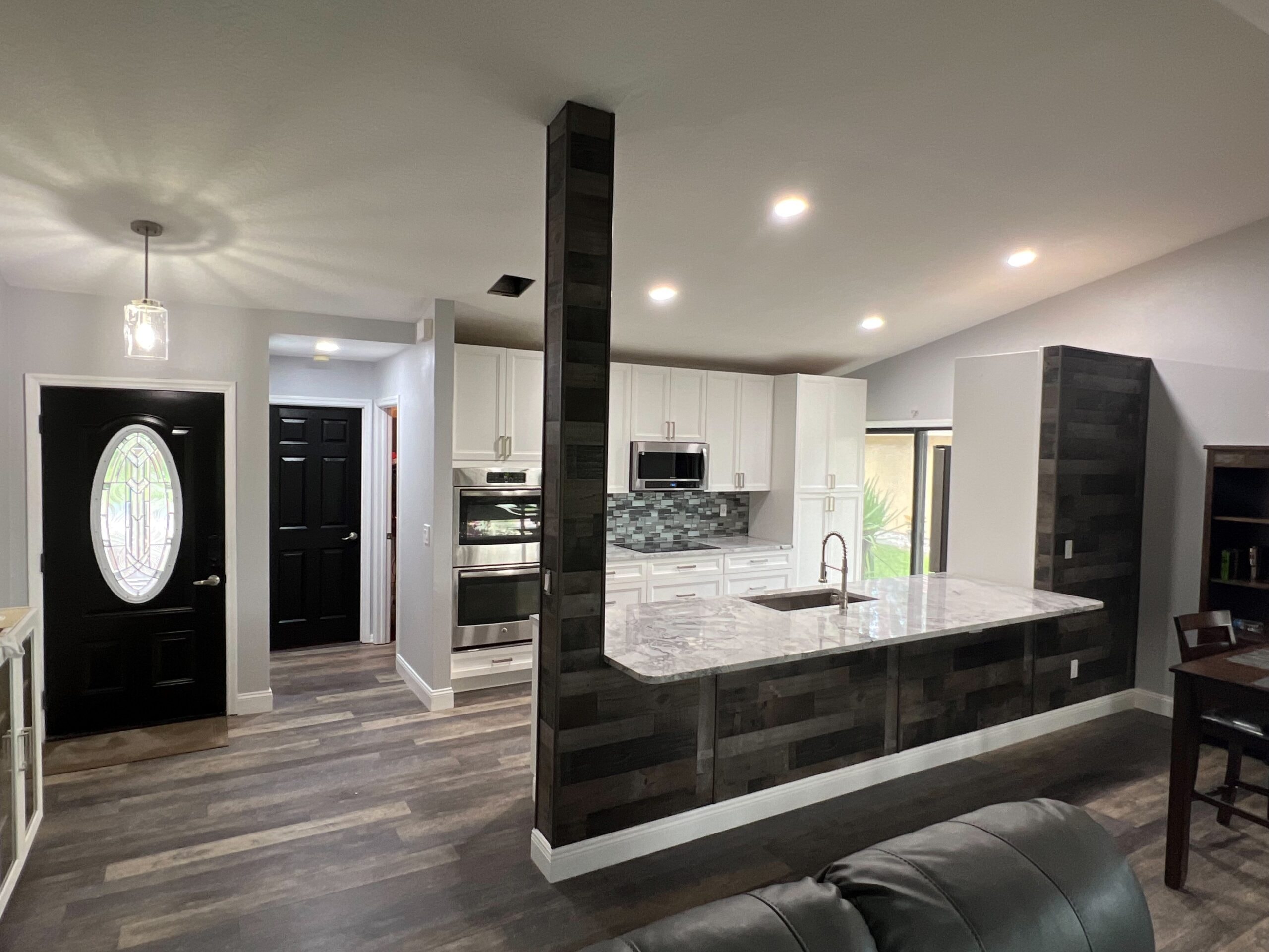 White and dark wood kitchen with marble peninsula mosaic backsplash and double wall ovens by 1 Stop Cabinets