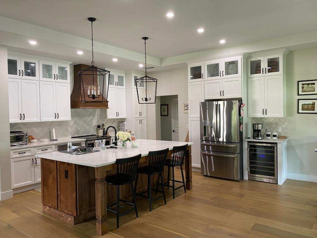 Two-tone gray and white flat panel kitchen with marble waterfall island gold hardware and dining area by 1 Stop Cabinets