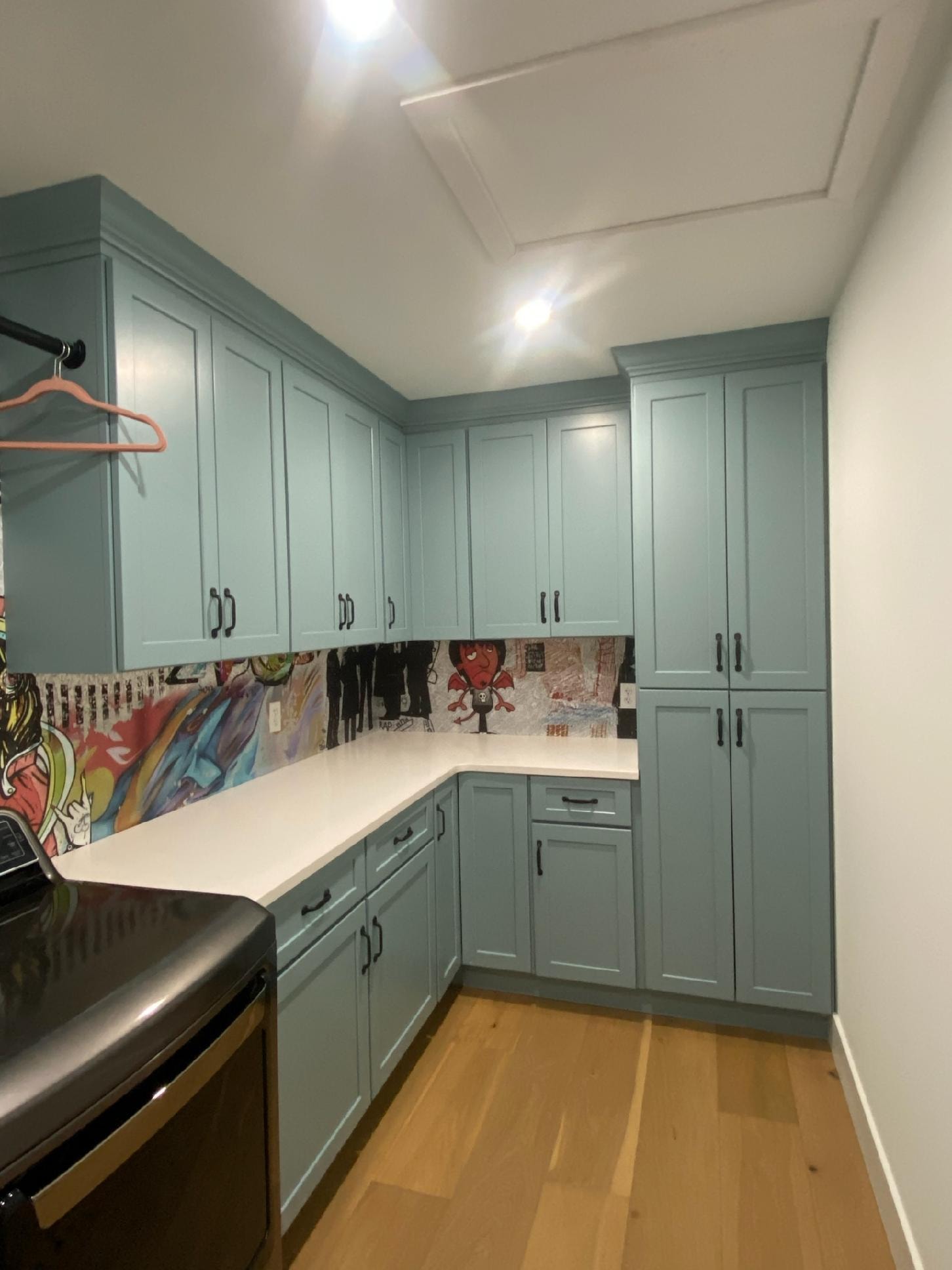 Mint green shaker laundry room with quartz countertops black hardware and graffiti art backsplash wide view by 1 Stop Cabinets