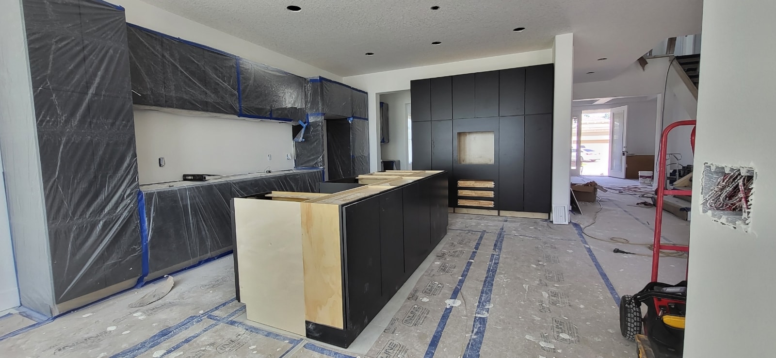 Matte black flat panel new construction kitchen under construction with large island and full-height pantry wall by 1 Stop Cabinets