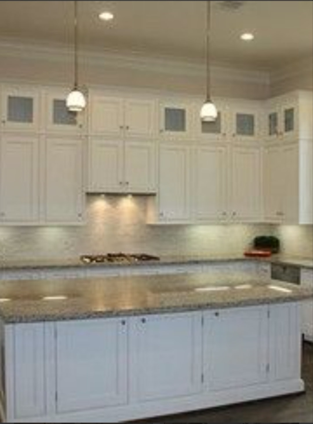White raised panel kitchen with granite island pendant lights glass upper cabinets and under-cabinet lighting by 1 Stop Cabinets