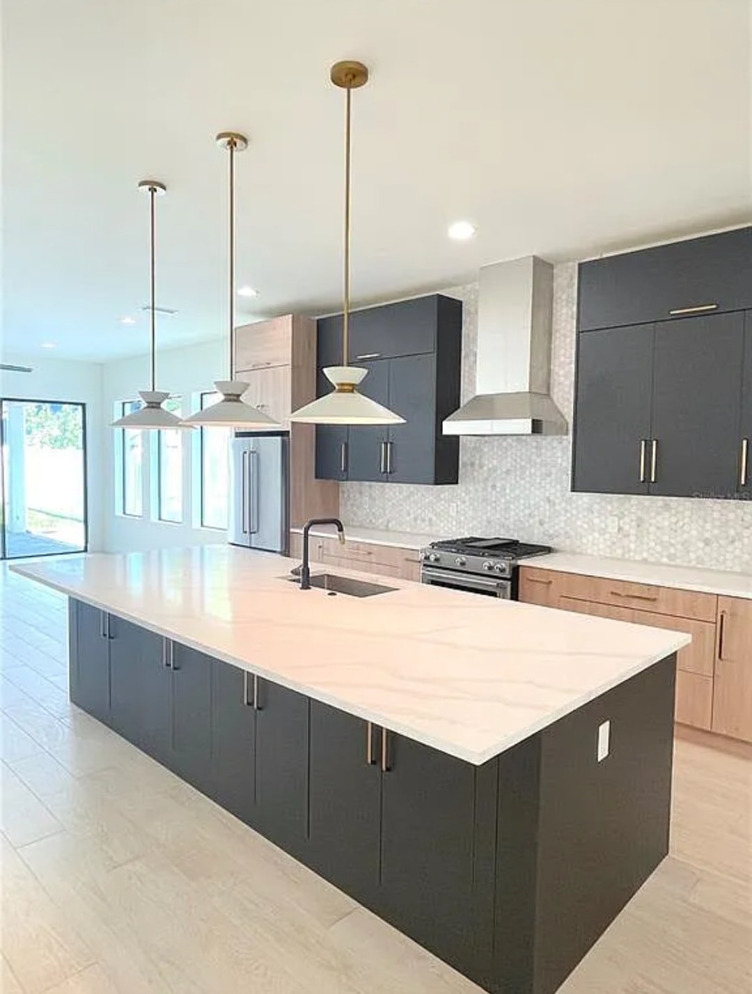 Two-tone charcoal and natural oak flat panel kitchen with quartz waterfall island and gold pendants by 1 Stop Cabinets