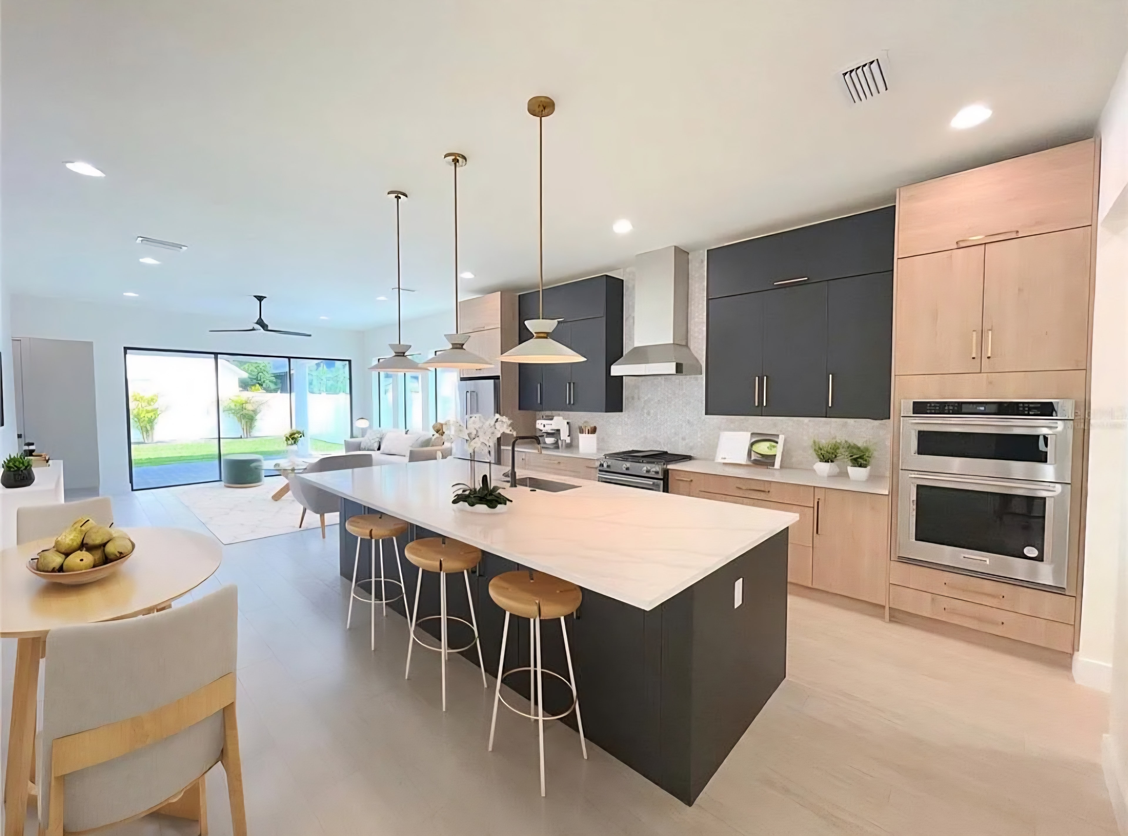 Two-tone charcoal and natural oak kitchen with quartz island wood bar stools and open concept living area by 1 Stop Cabinets
