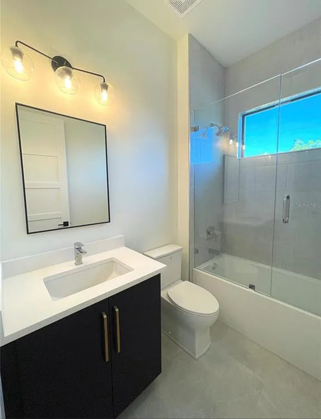 Dark flat panel bathroom vanity with white quartz countertop black framed mirror and glass shower enclosure by 1 Stop Cabinets