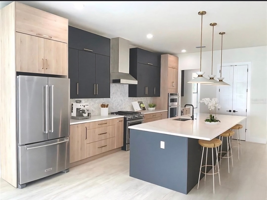 Two-tone charcoal and natural oak kitchen with quartz island gold pendants and KitchenAid refrigerator wide view by 1 Stop Cabinets