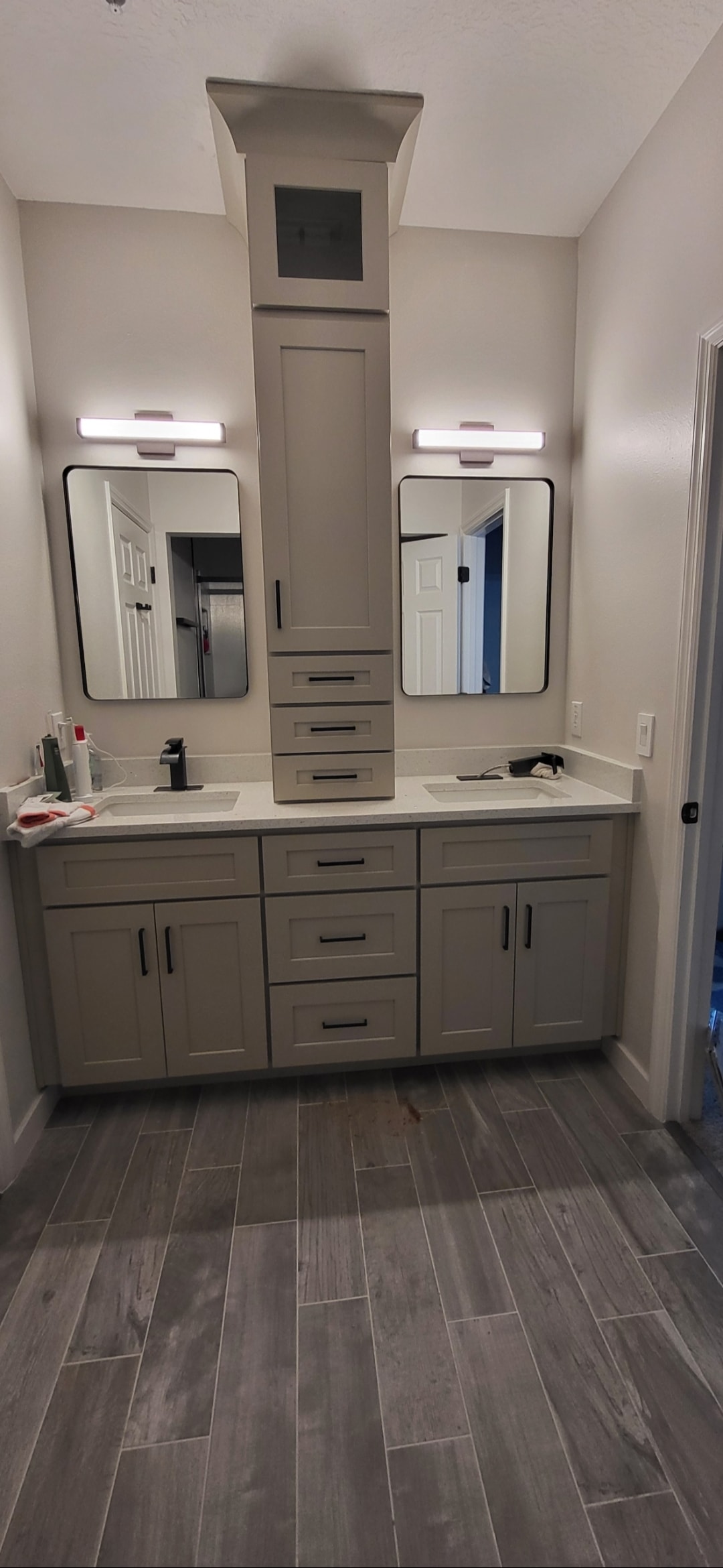 Gray shaker double bathroom vanity with white quartz countertop center tower cabinet black hardware and wood-look tile floors by 1 Stop Cabinets