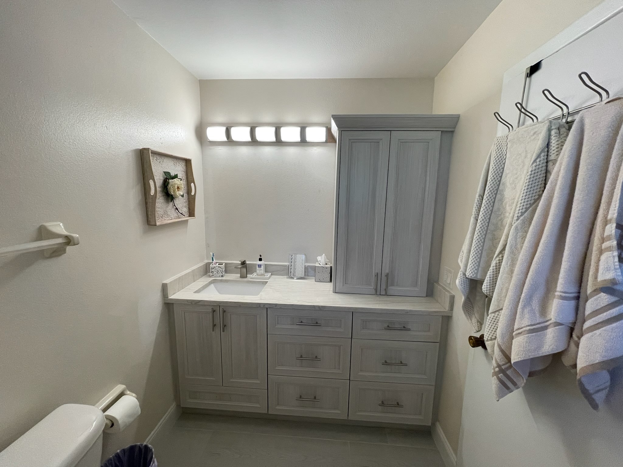 Light gray raised panel single bathroom vanity with white quartz countertop wall cabinet and chrome hardware by 1 Stop Cabinets