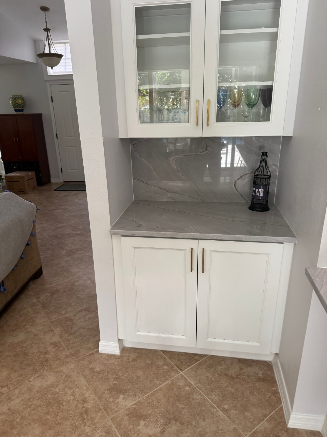White raised panel built-in bar nook with glass-front upper cabinets gray marble quartz countertop and gold hardware by 1 Stop Cabinets