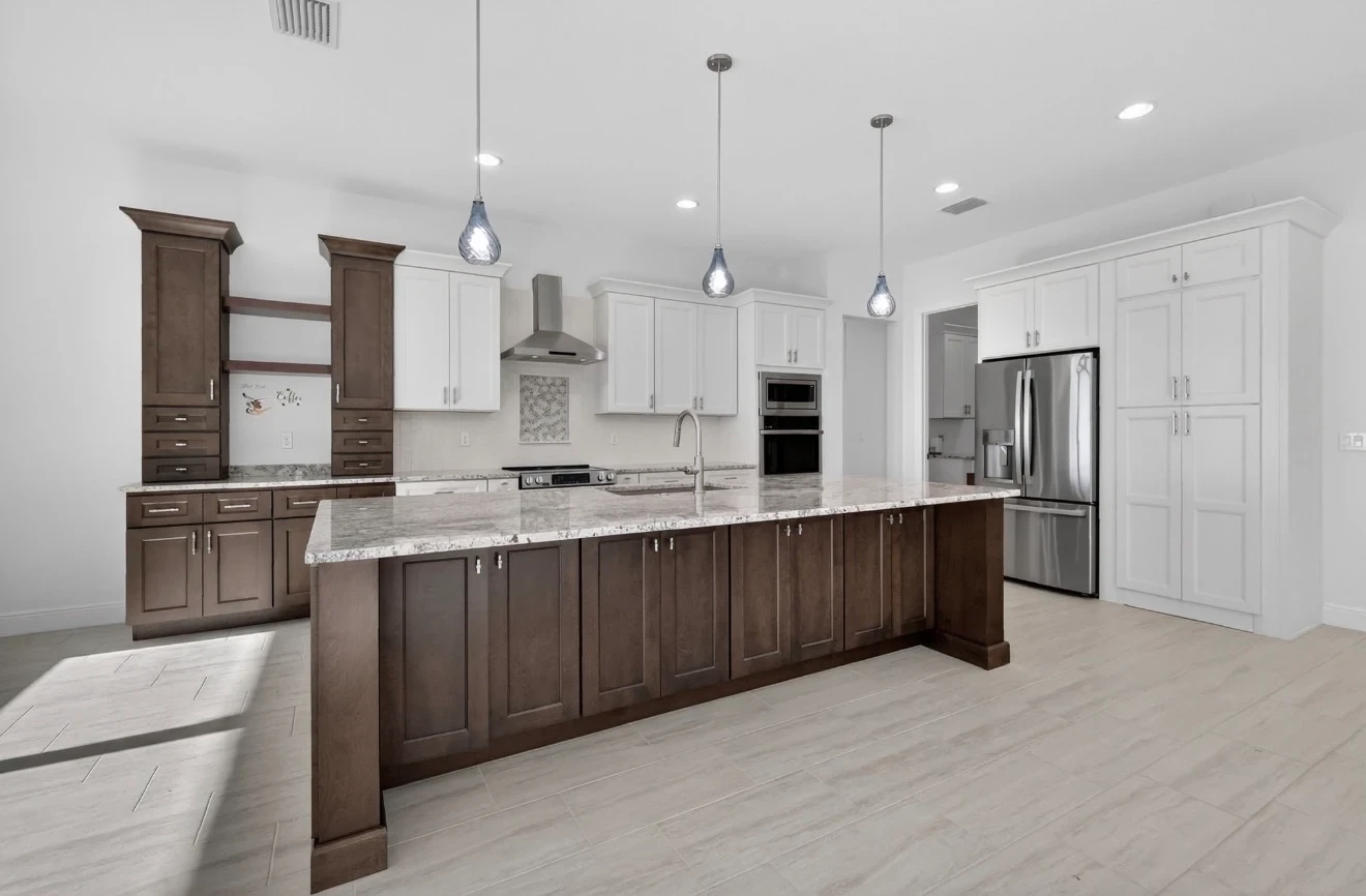 Two-tone dark walnut and white raised panel kitchen with granite island blue teardrop pendants stainless appliances and light wood-look tile floors by 1 Stop Cabinets