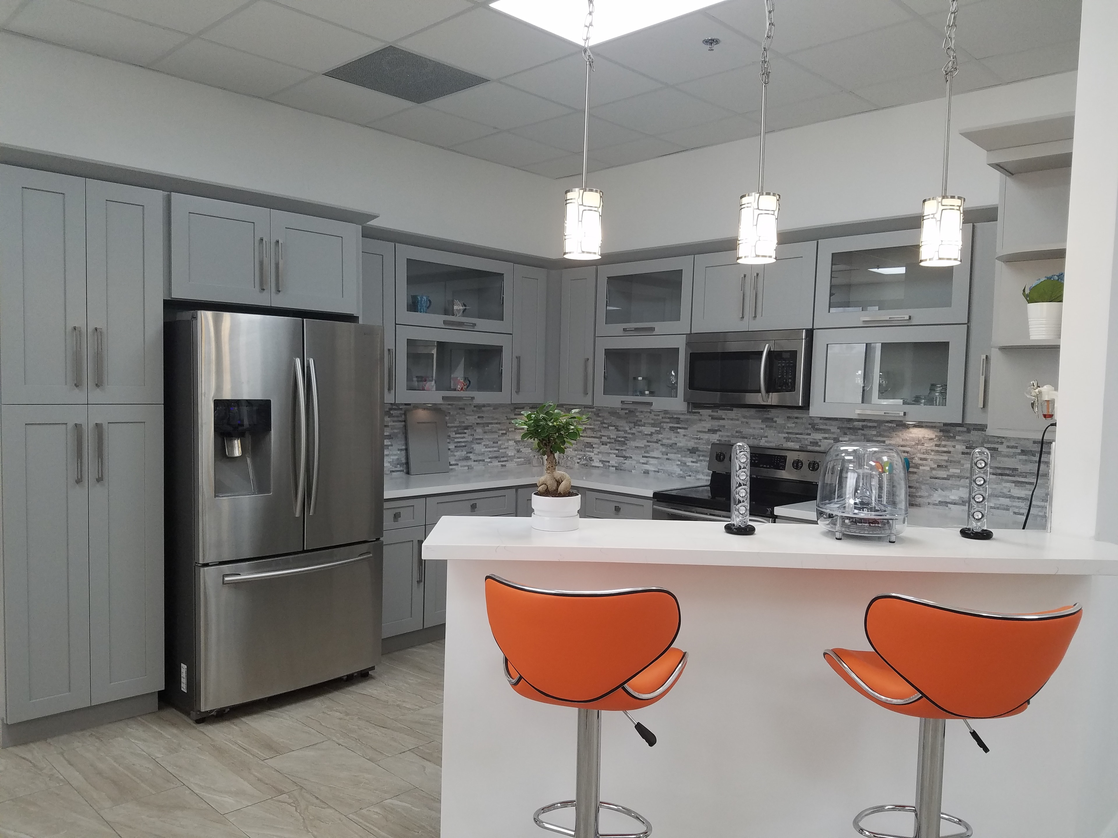 Gray shaker kitchen with orange bar stools and stainless appliances by 1 Stop Cabinets
