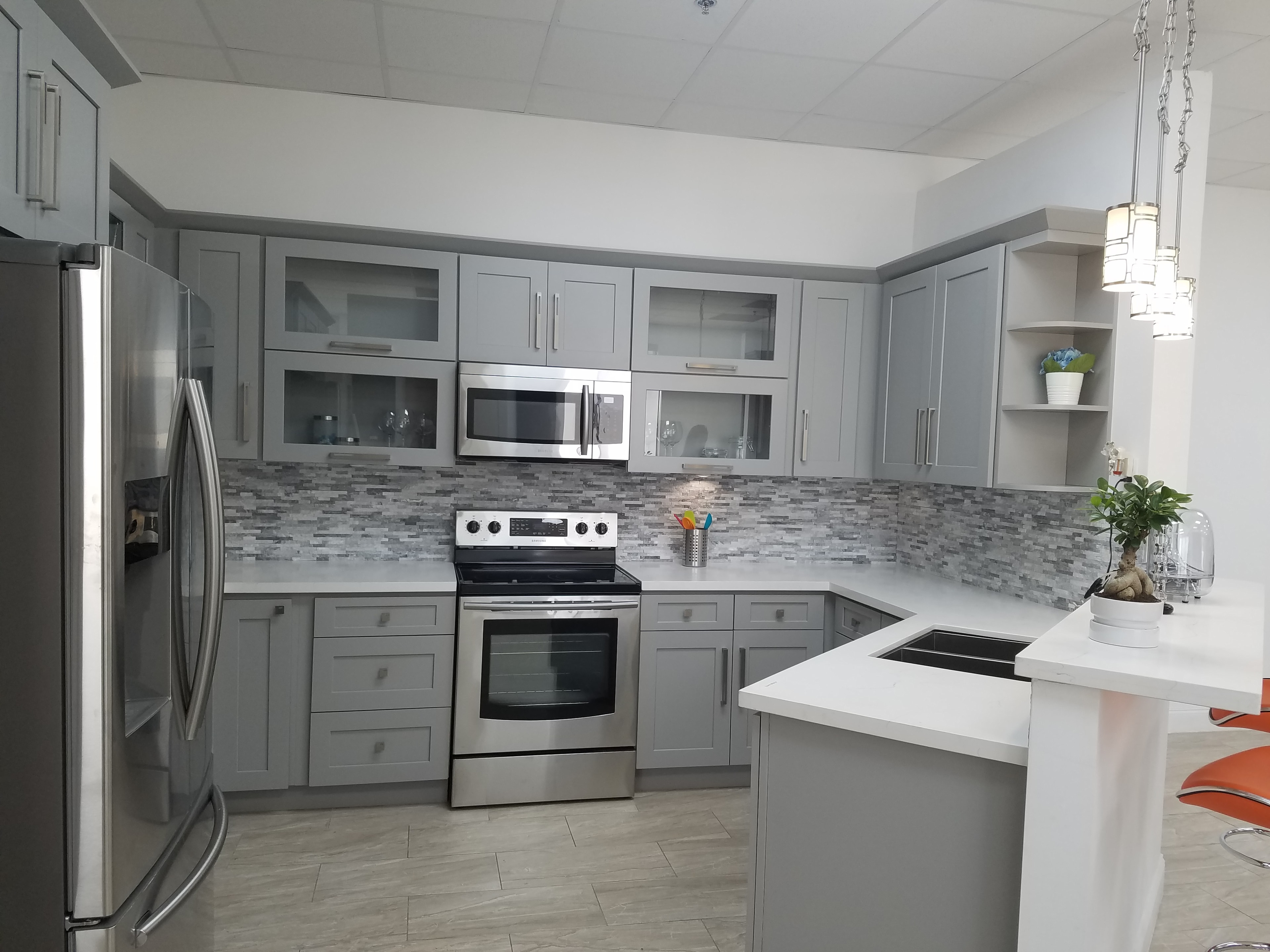 Gray shaker kitchen with glass cabinet doors and mosaic backsplash by 1 Stop Cabinets