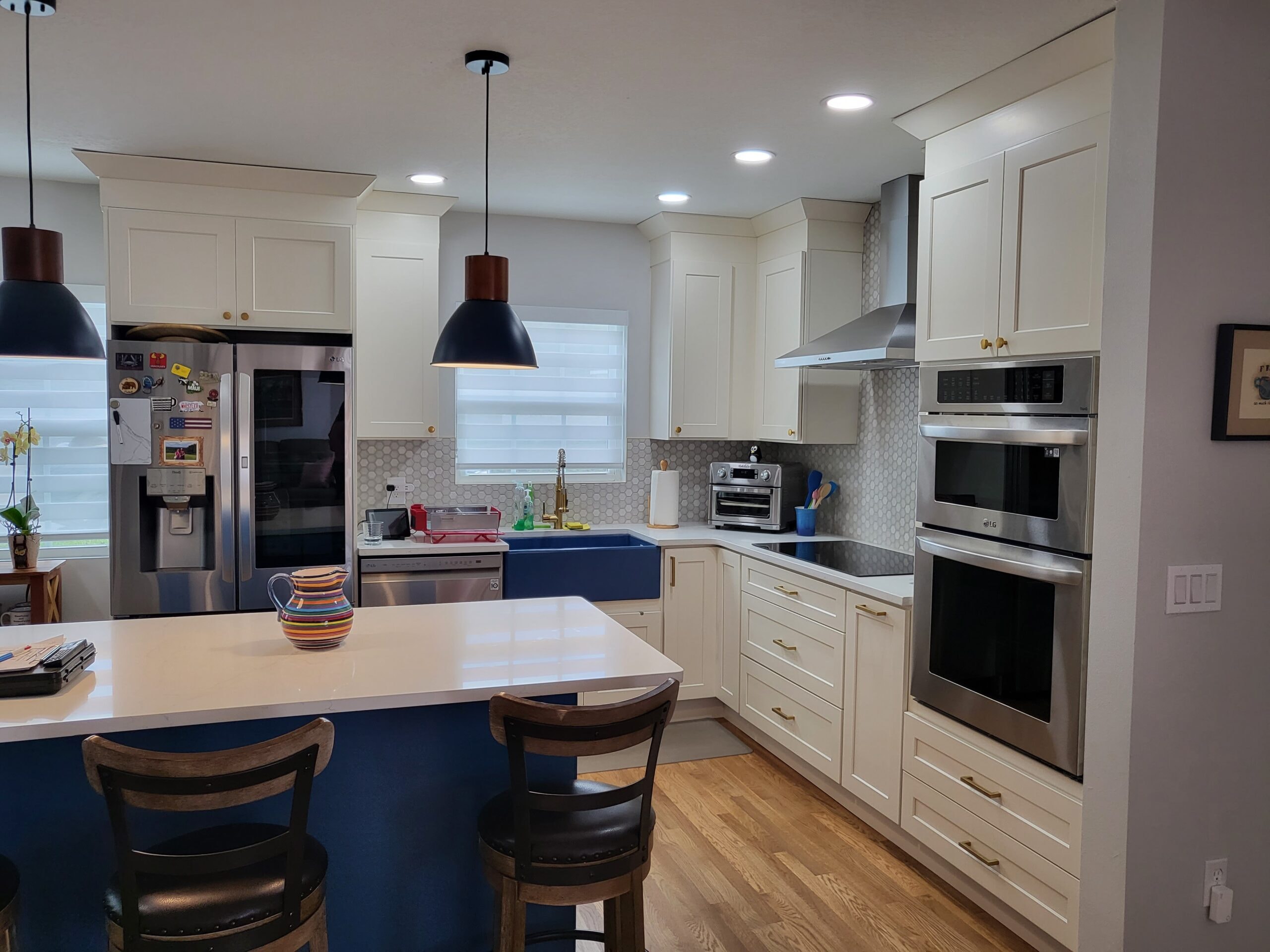 White shaker kitchen with navy blue island and farmhouse sink by 1 Stop Cabinets