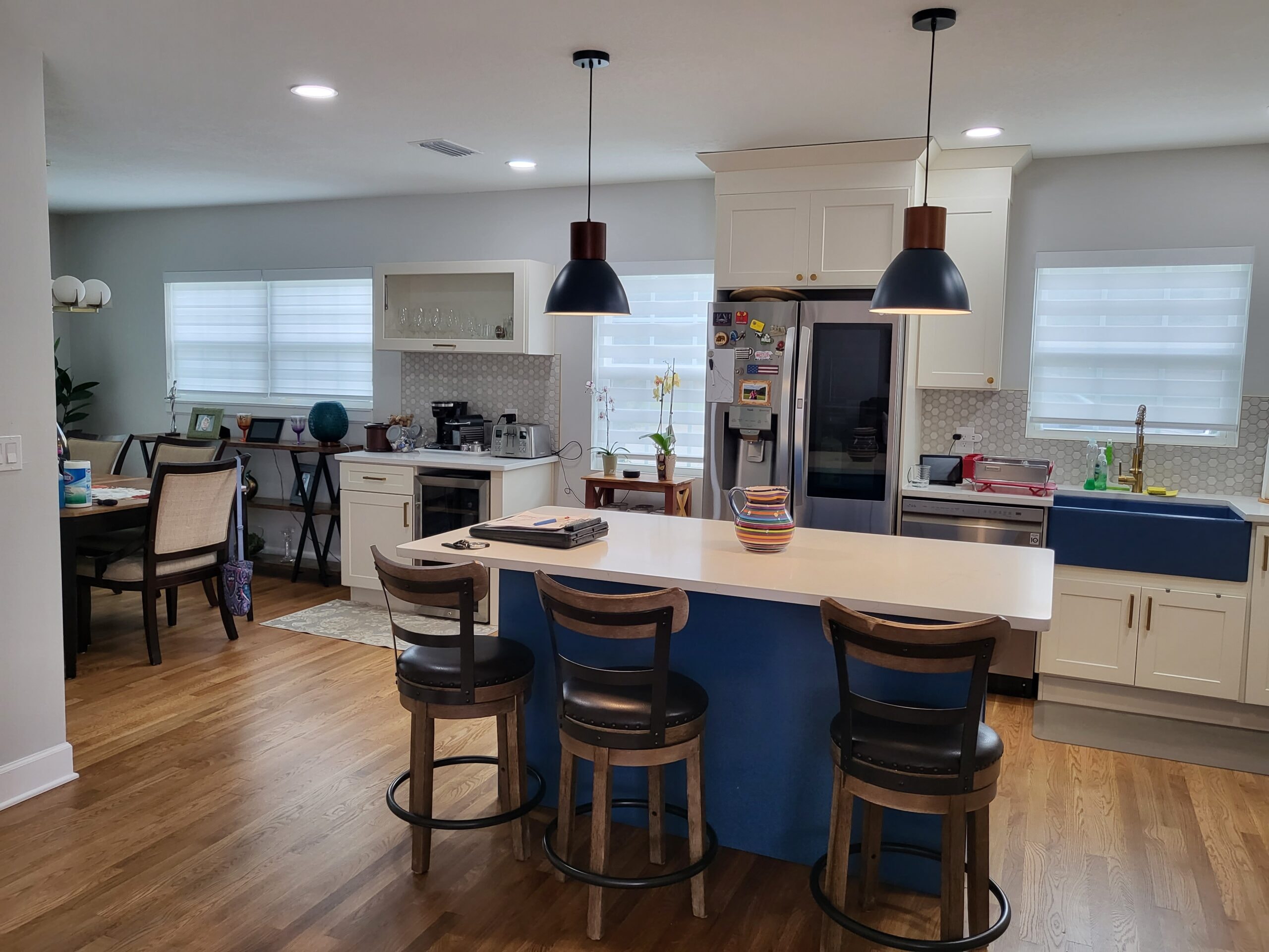 White shaker kitchen with blue island and black pendant lights by 1 Stop Cabinets