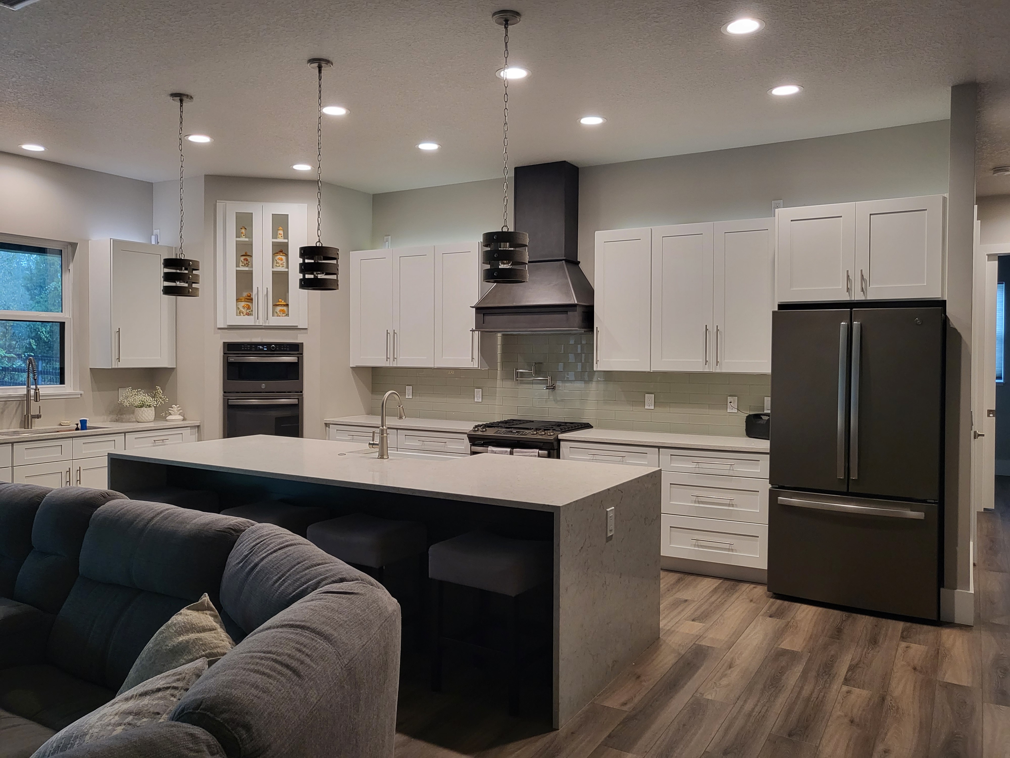 White shaker kitchen with dark island and black range hood by 1 Stop Cabinets