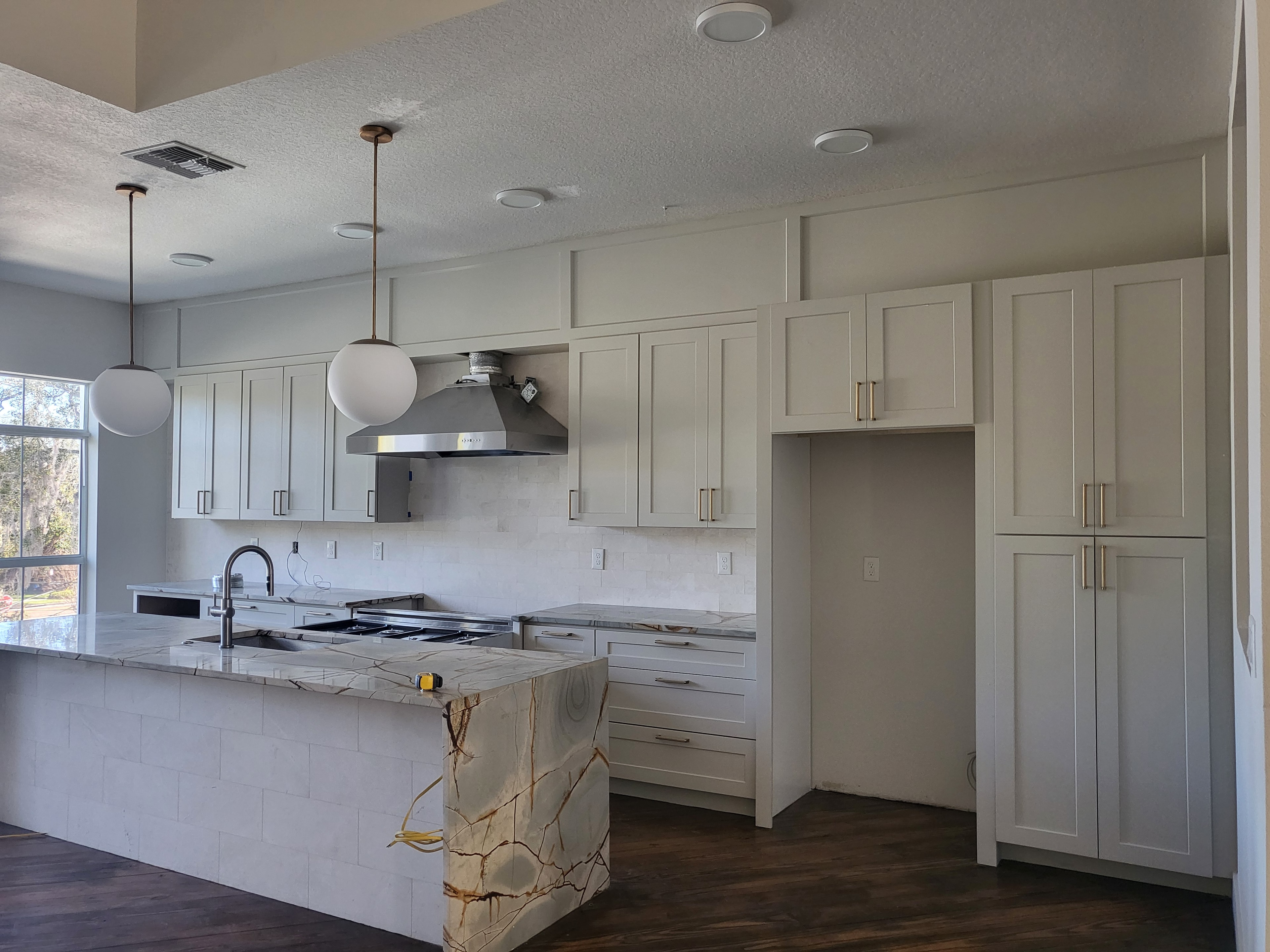 White shaker kitchen with dramatic quartzite island waterfall by 1 Stop Cabinets