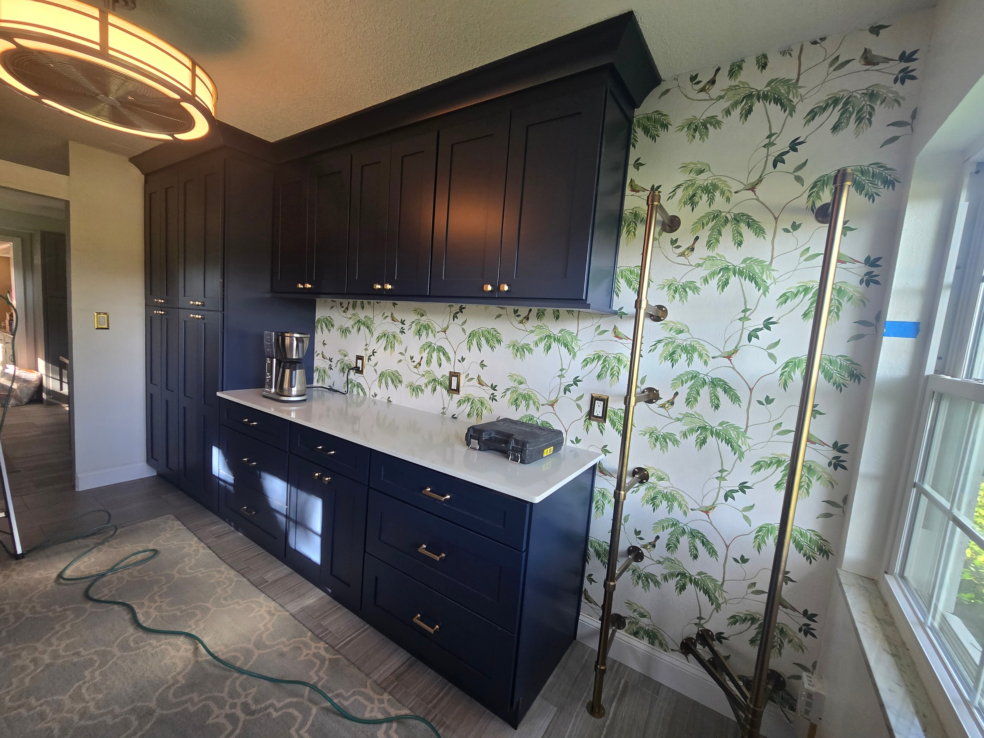 Navy blue shaker cabinets with botanical wallpaper and brass hardware by 1 Stop Cabinets