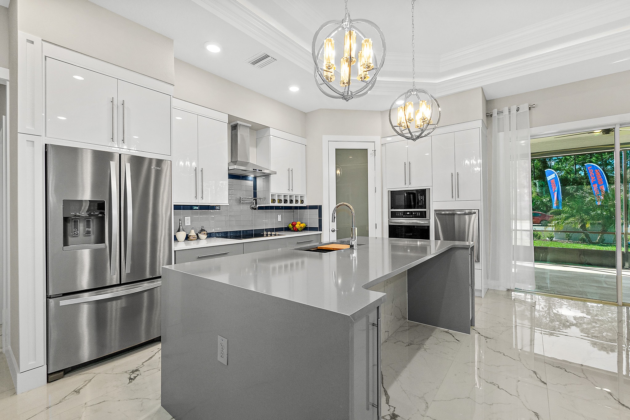 White and gray two-tone kitchen with globe chandeliers and marble floors by 1 Stop Cabinets
