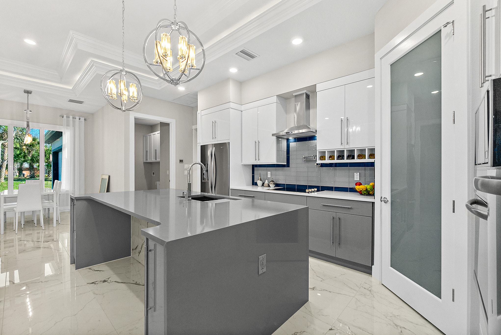White and gray kitchen with globe chandeliers and open concept dining by 1 Stop Cabinets