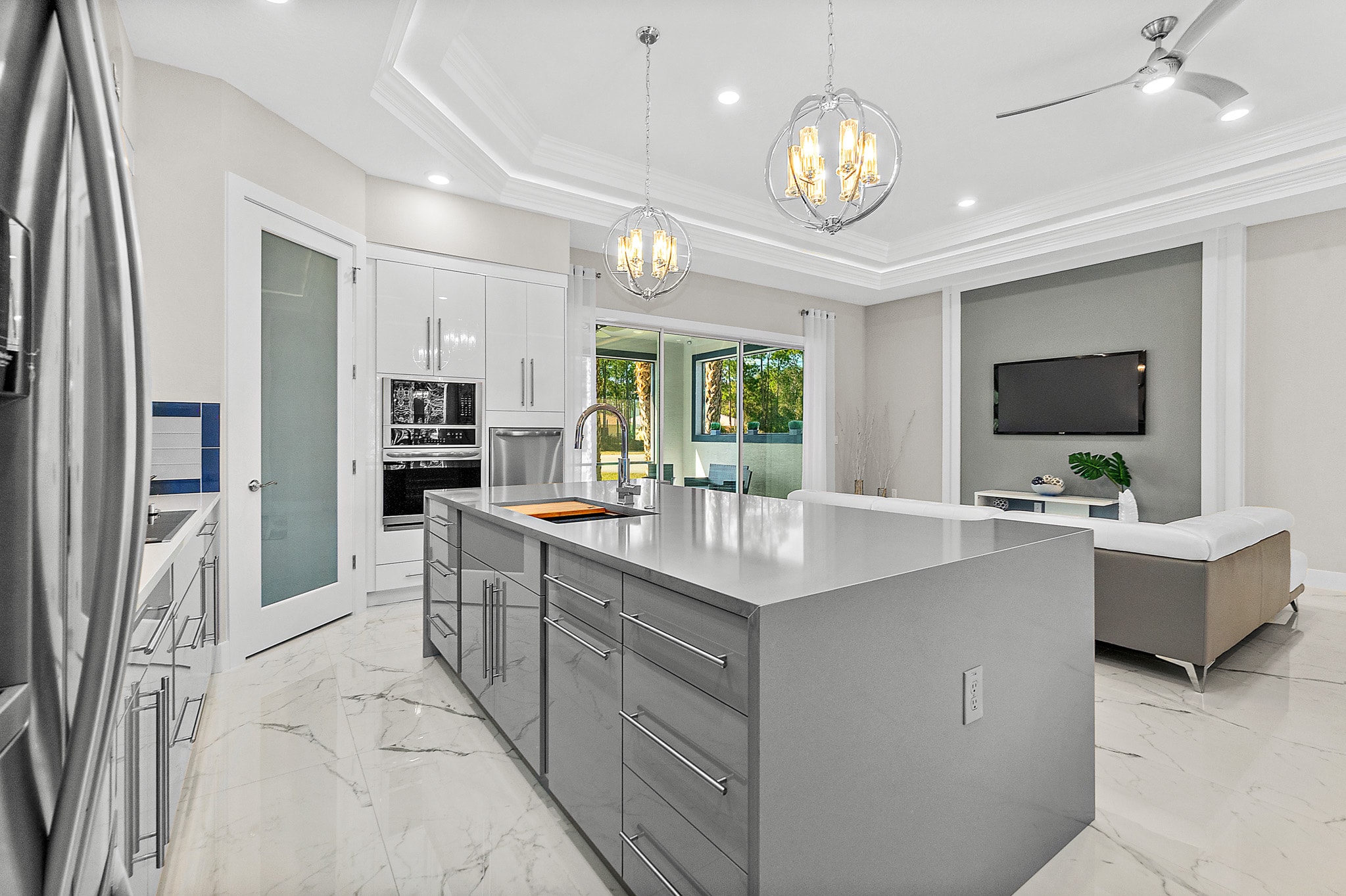 White and gray kitchen with large island and view to living room by 1 Stop Cabinets