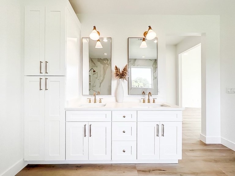 White shaker double bathroom vanity with gold fixtures and linen tower by 1 Stop Cabinets