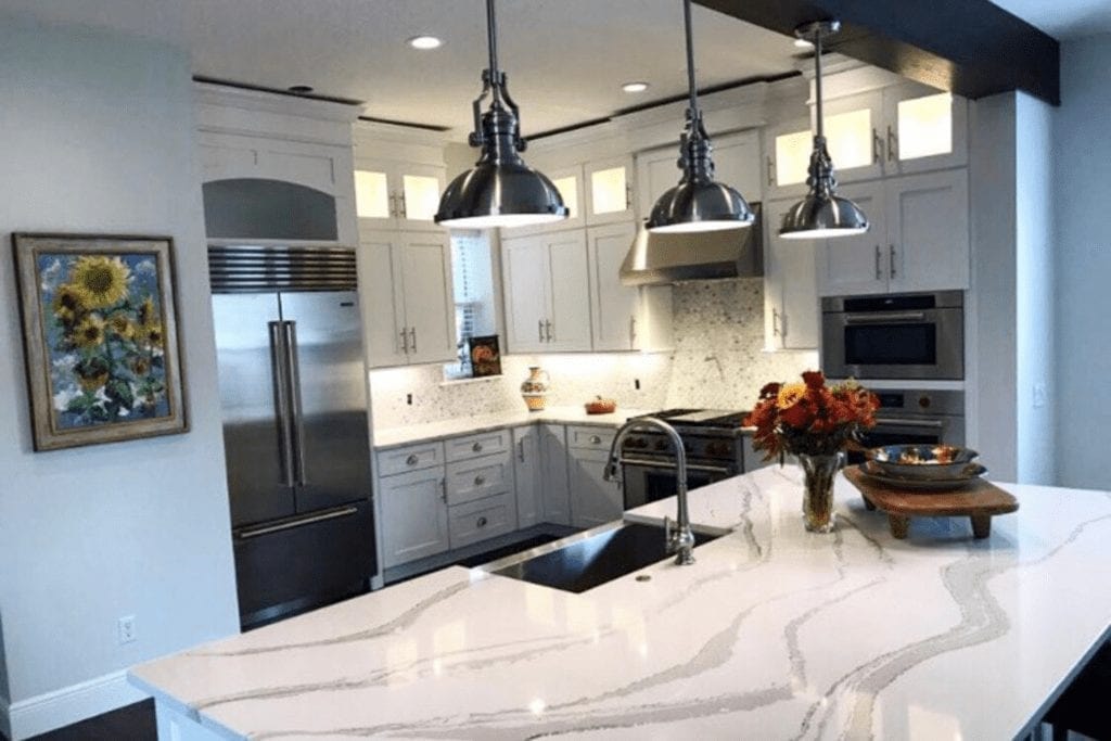 White kitchen with marble countertops and pendant lights by 1 Stop Cabinets