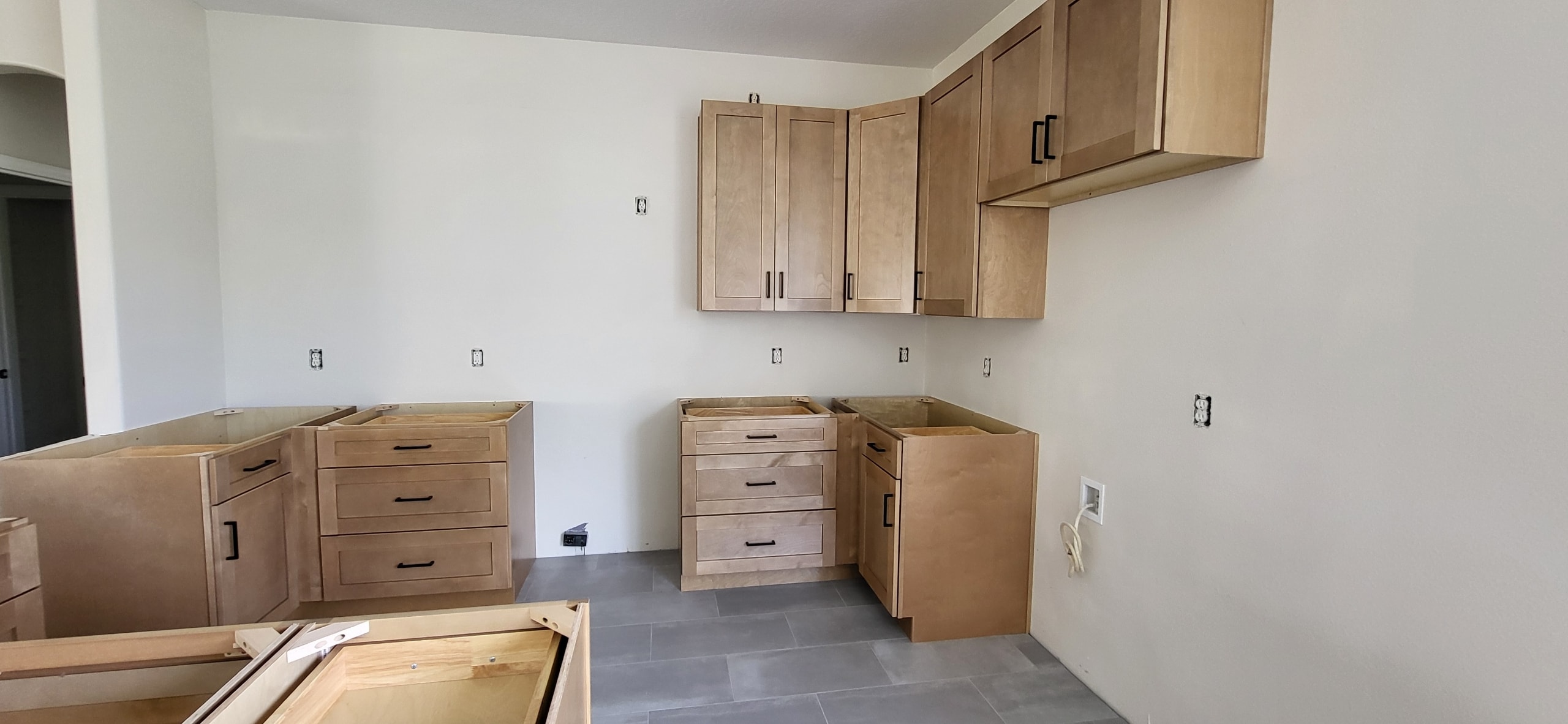 Natural maple shaker kitchen under construction with black hardware by 1 Stop Cabinets