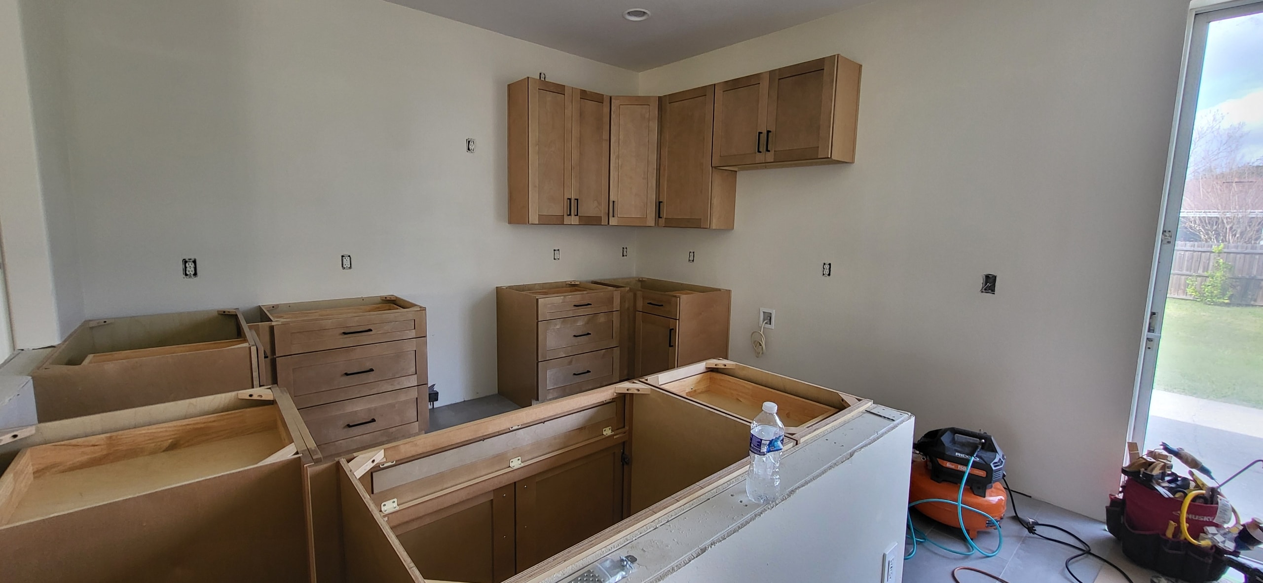 Natural maple shaker kitchen under construction with island and black hardware by 1 Stop Cabinets