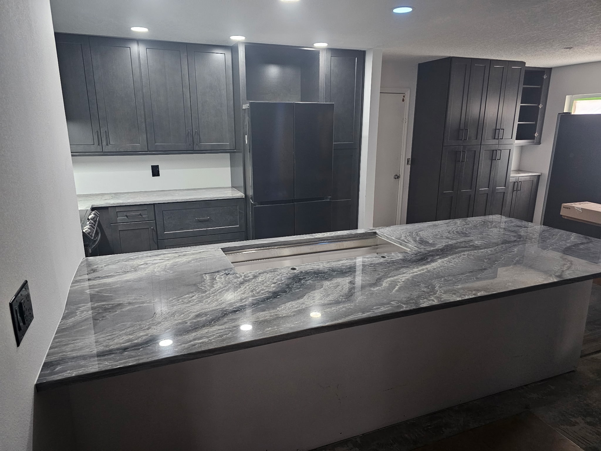 Dark gray shaker kitchen with quartzite island and full-height pantry cabinets by 1 Stop Cabinets
