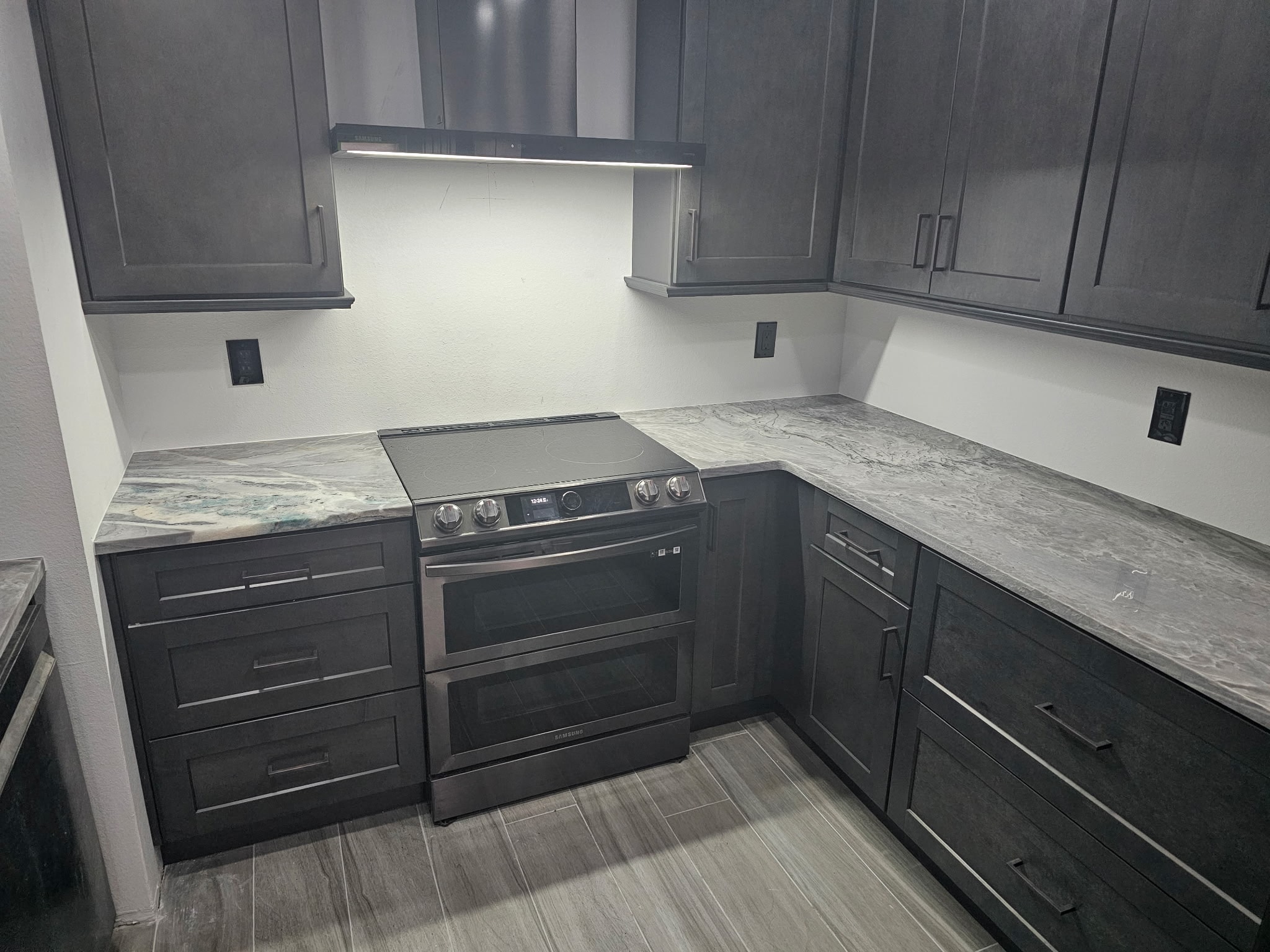 Dark gray shaker kitchen with quartzite countertops and Samsung double oven by 1 Stop Cabinets