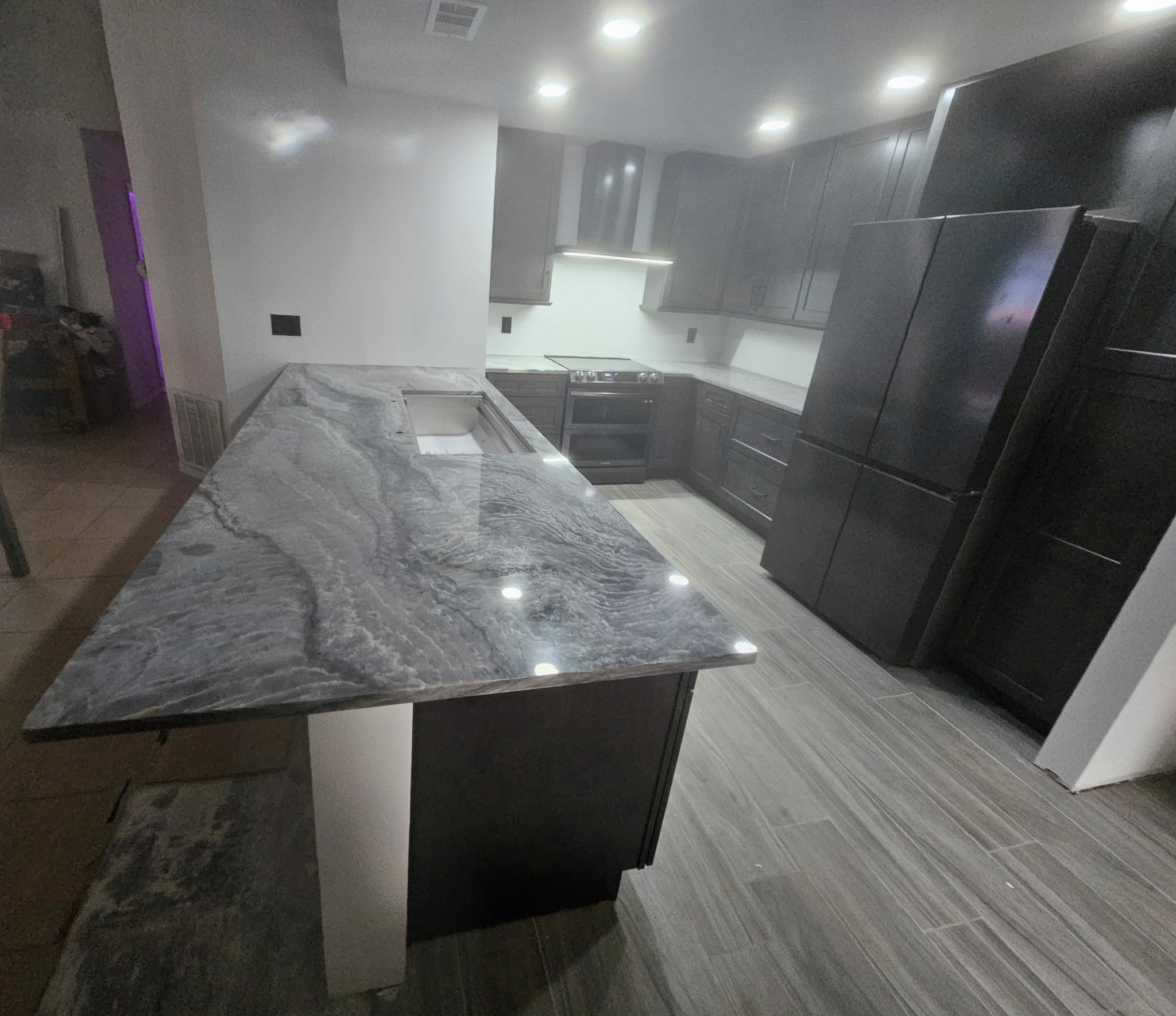 Dark gray shaker kitchen with quartzite island and open concept layout by 1 Stop Cabinets
