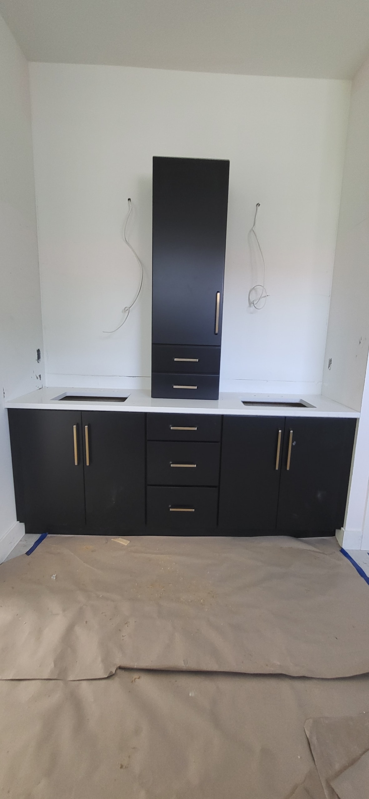 Black flat panel bathroom vanity under construction with white quartz countertop and gold hardware by 1 Stop Cabinets