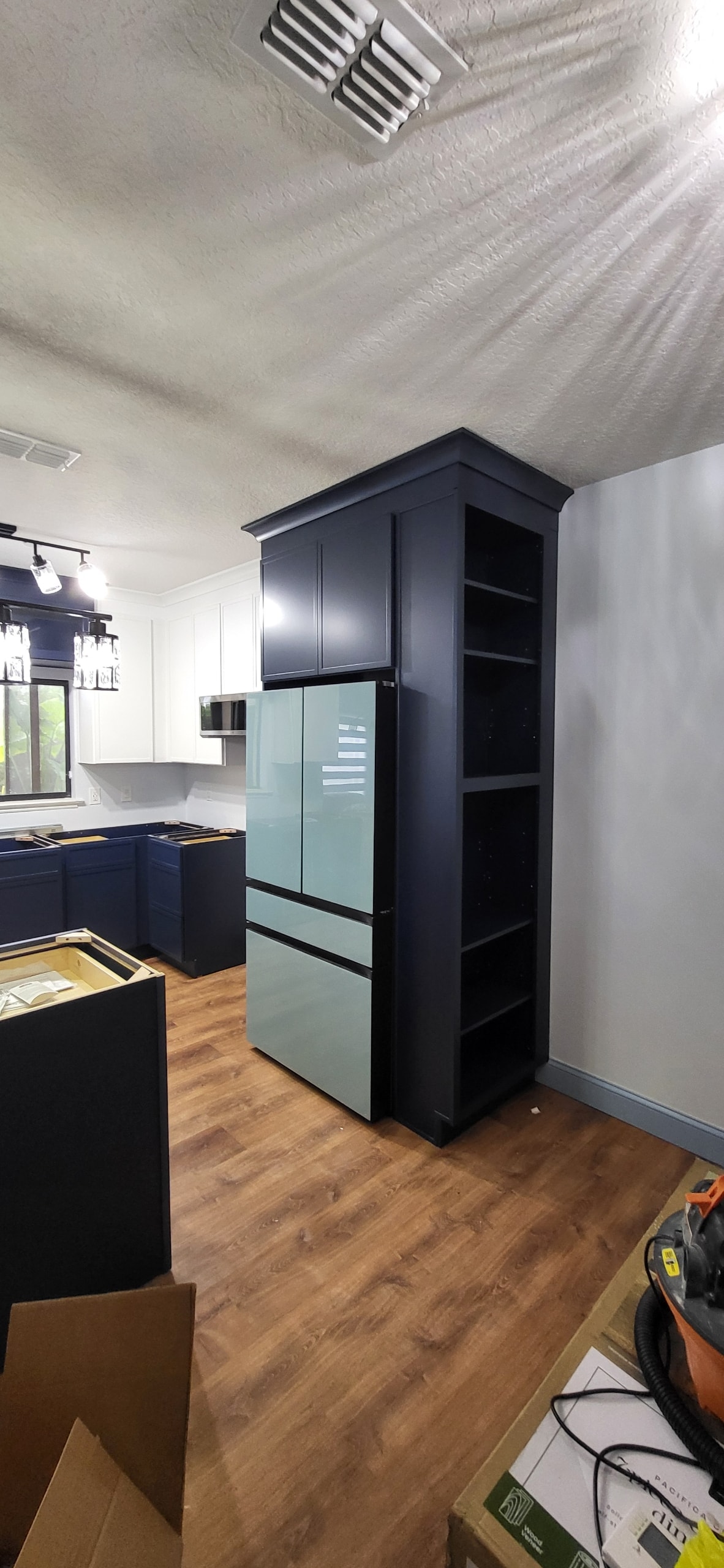 Navy blue shaker kitchen under construction with tall pantry cabinet and mint refrigerator by 1 Stop Cabinets