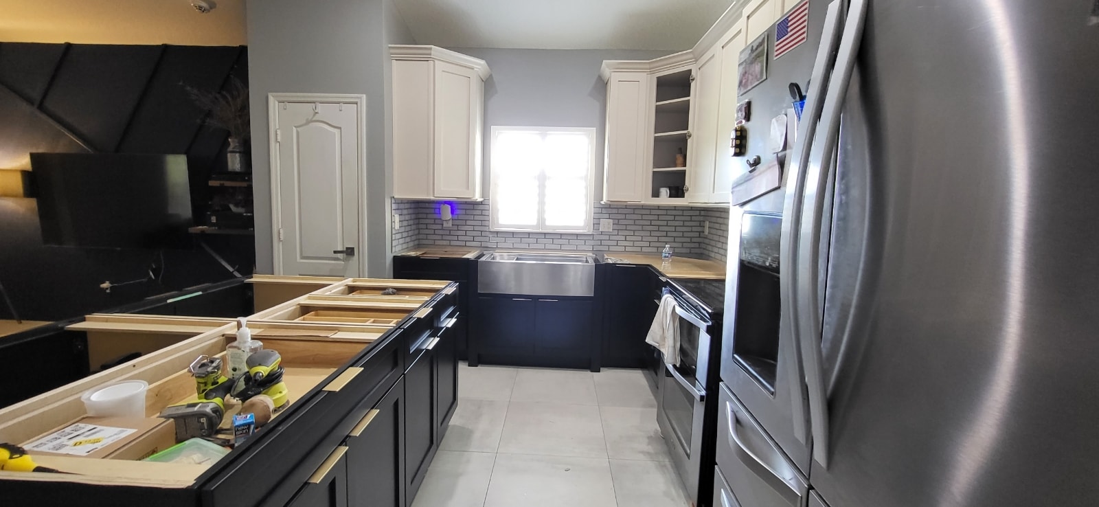Two-tone black and white kitchen under construction with farmhouse sink and subway tile backsplash by 1 Stop Cabinets