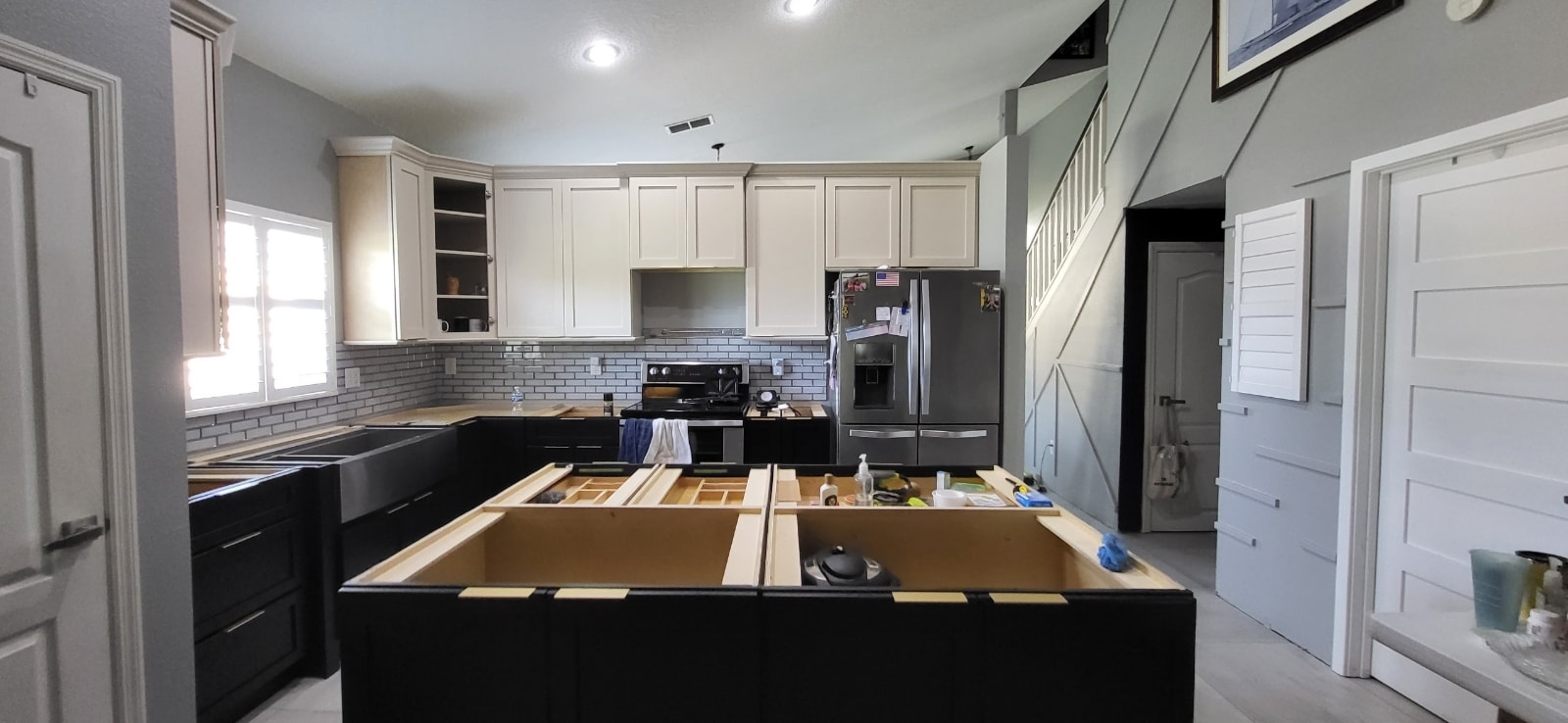 Two-tone black and white kitchen under construction with large island and open concept layout by 1 Stop Cabinets