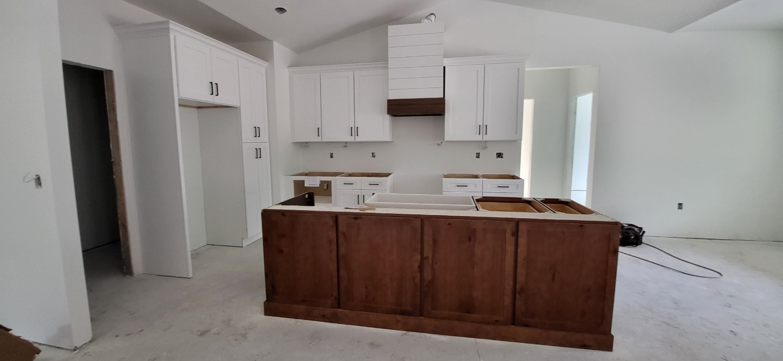 White shaker new construction kitchen with rustic wood island and shiplap range hood by 1 Stop Cabinets