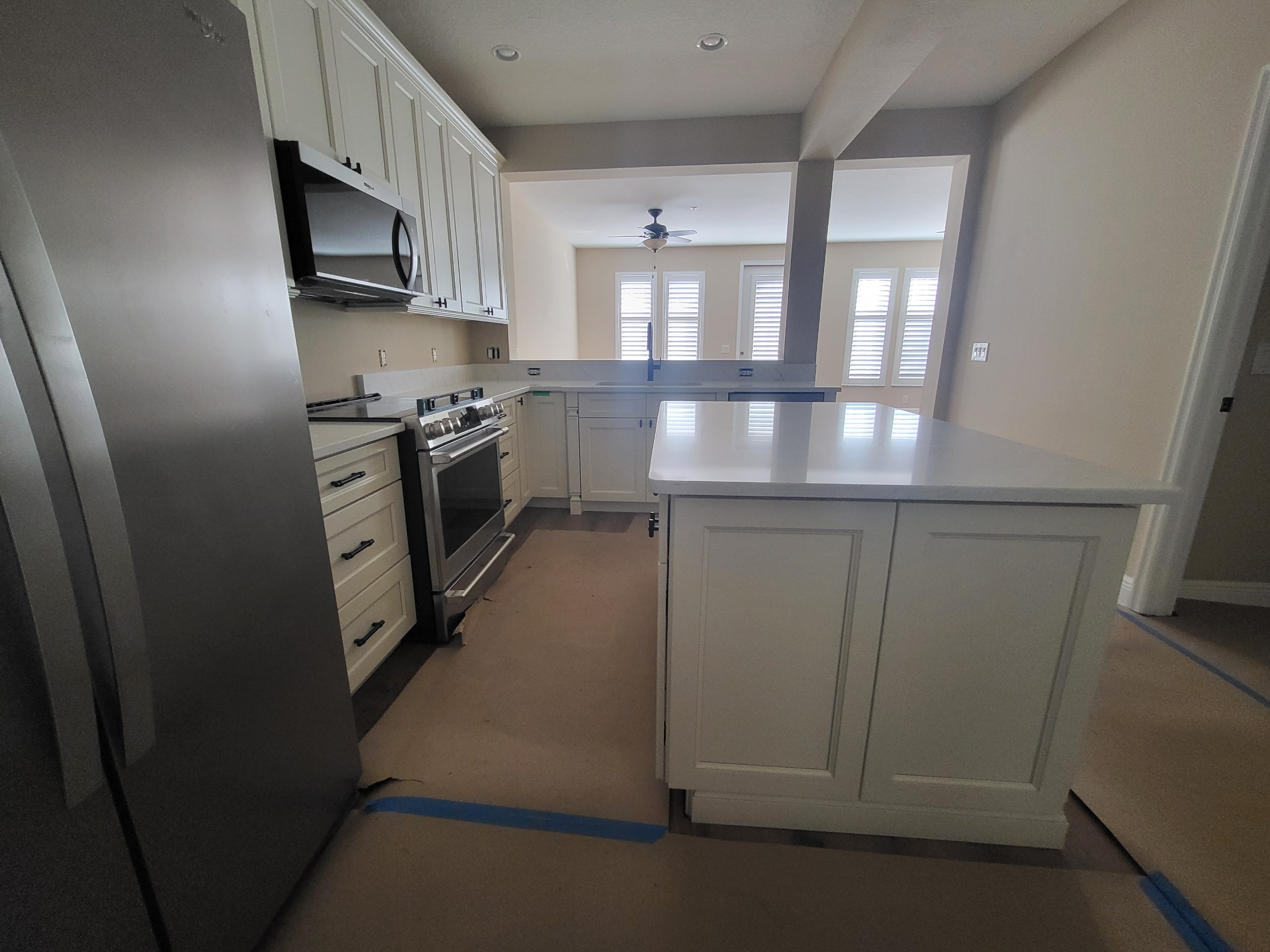 White raised panel kitchen with quartz countertops and plantation shutters by 1 Stop Cabinets