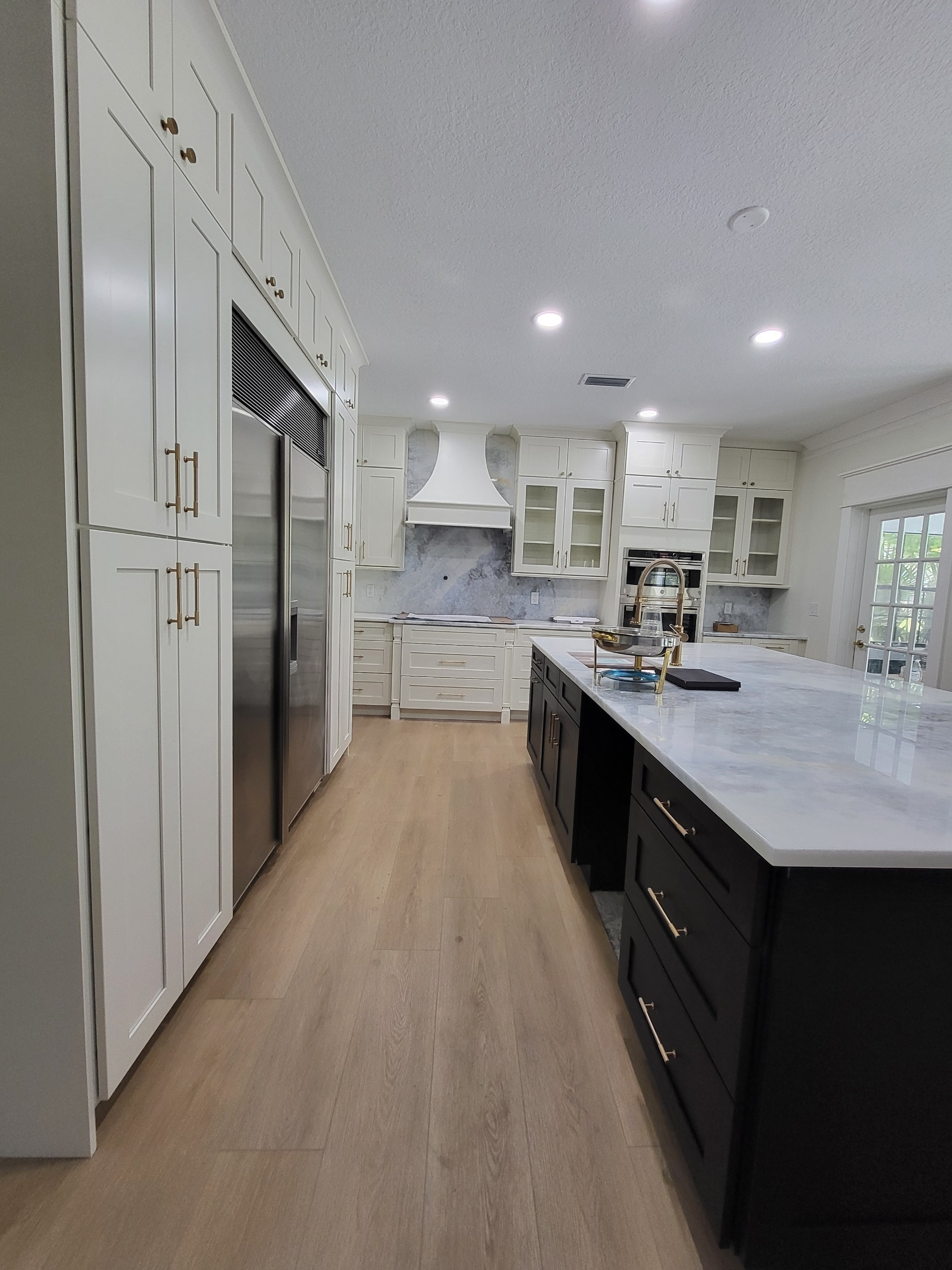 Two-tone white and black shaker kitchen with marble backsplash and gold hardware by 1 Stop Cabinets