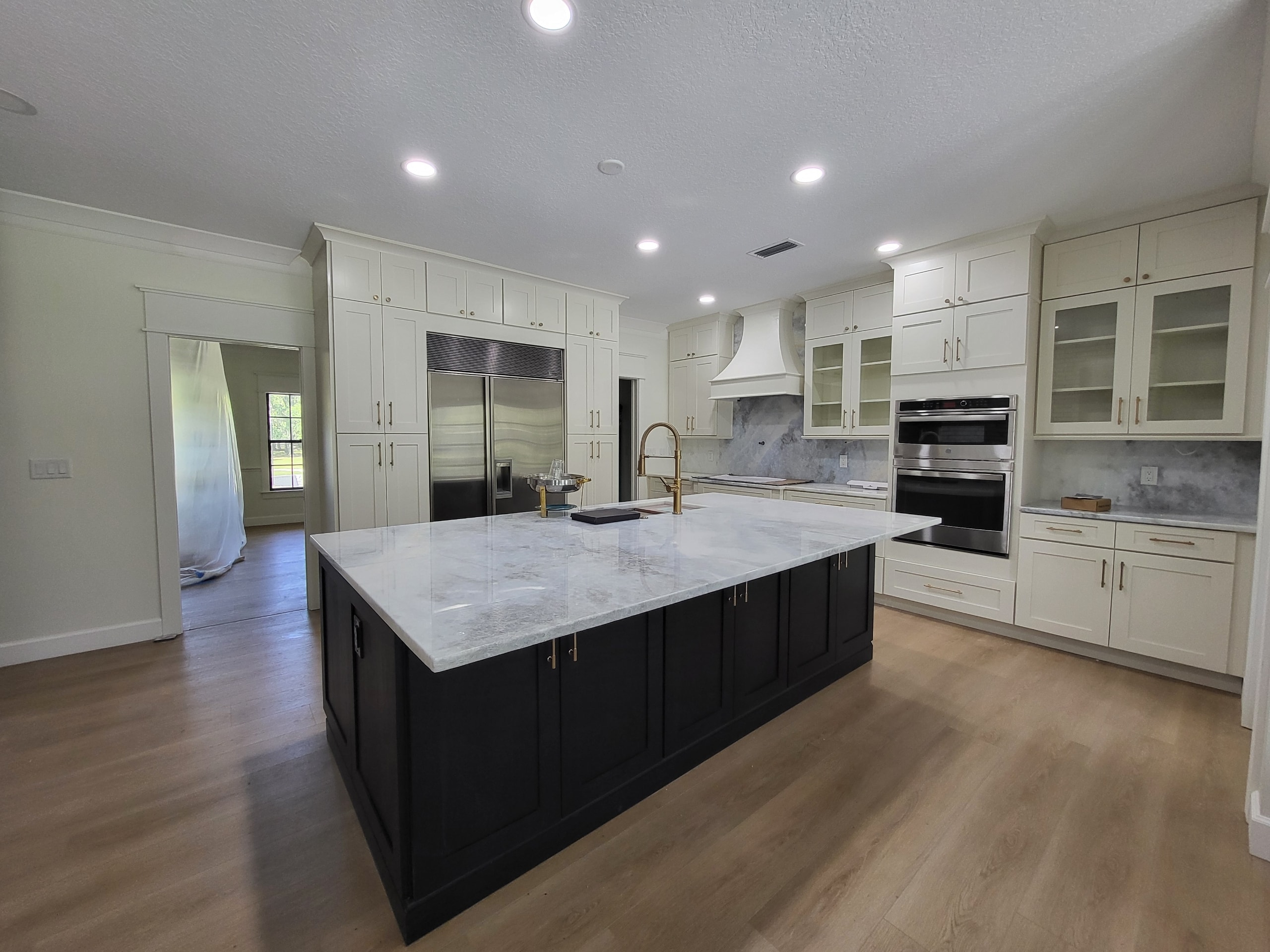 Two-tone white and black shaker kitchen with marble island and gold faucet by 1 Stop Cabinets