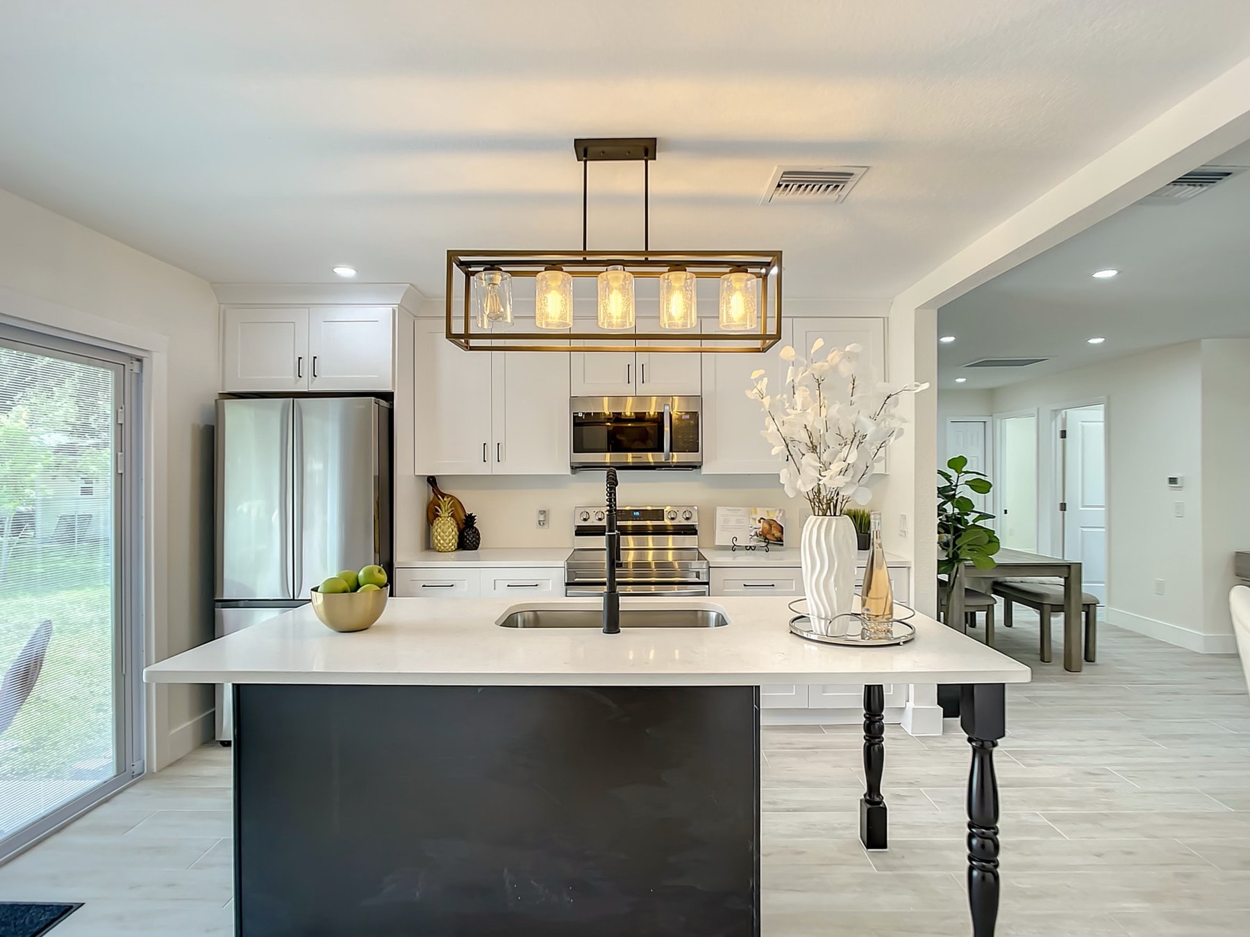 White and black two-tone kitchen with quartz island brass cage pendant light and black hardware by 1 Stop Cabinets