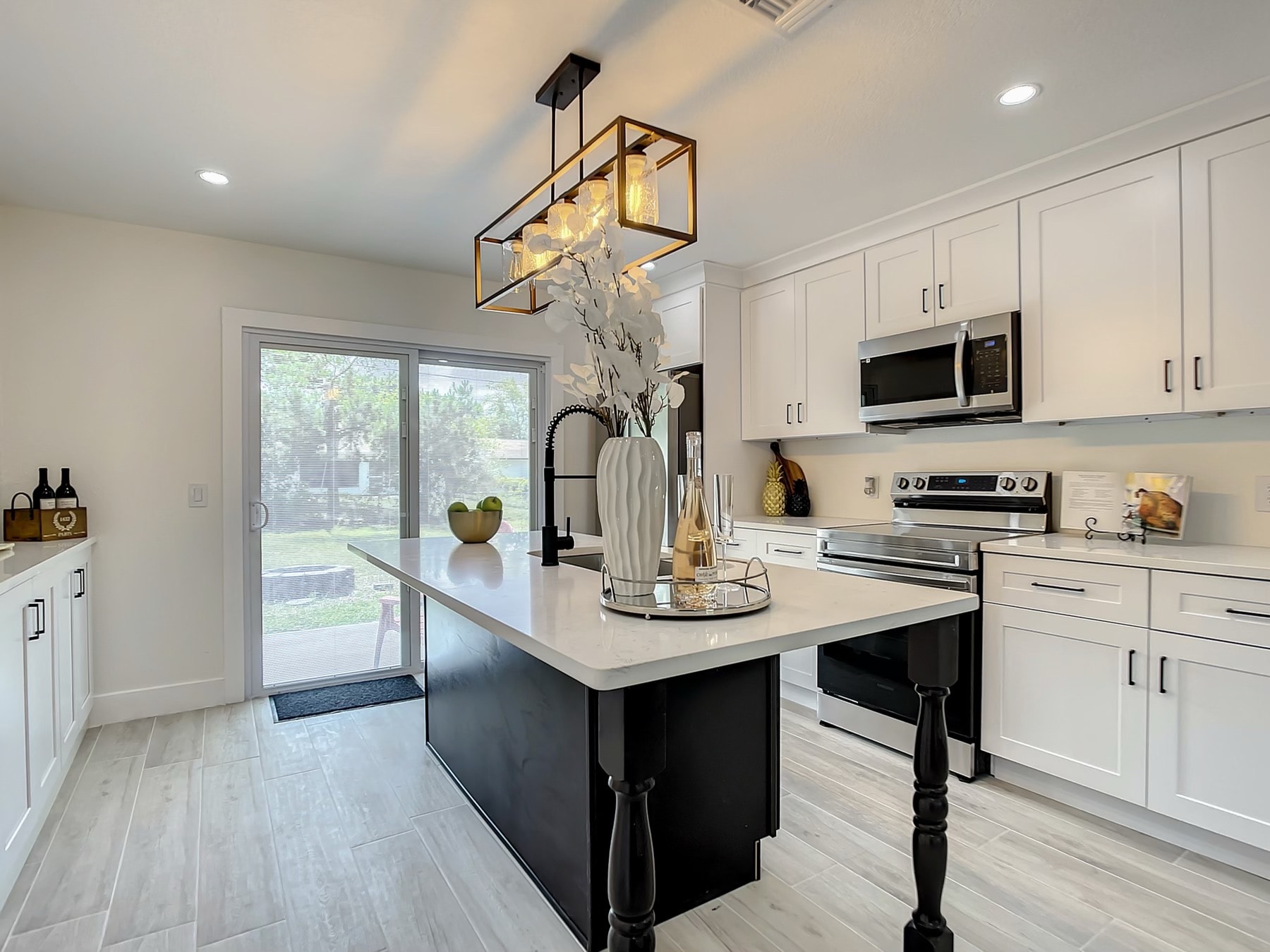 White and black two-tone kitchen with quartz island and view to backyard by 1 Stop Cabinets