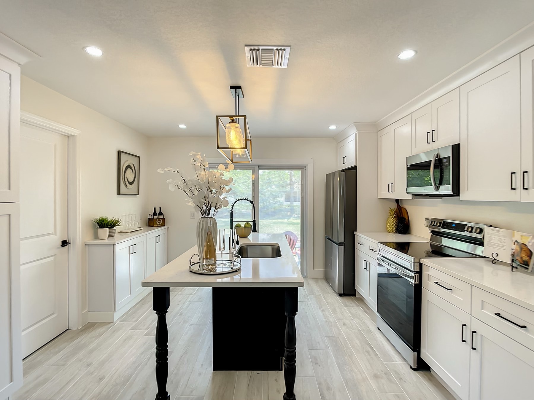 White and black two-tone kitchen with quartz island and full galley view by 1 Stop Cabinets